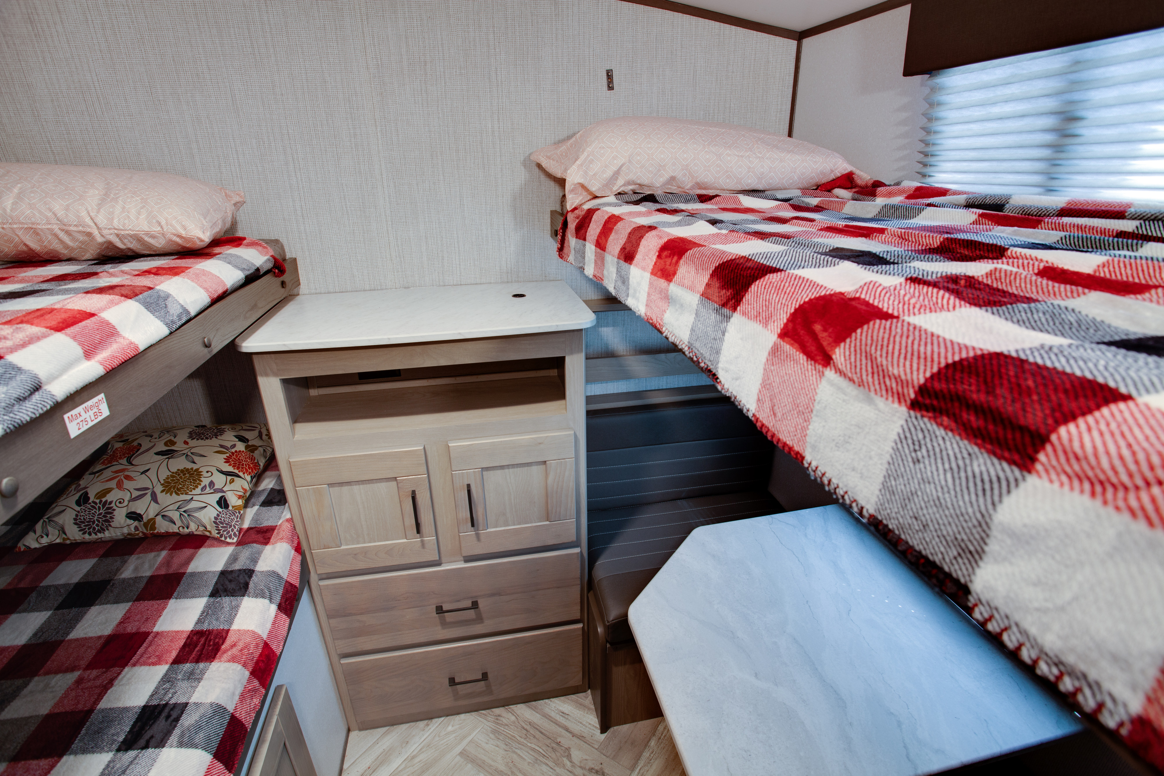 Cozy RV rental interior features bunk beds with plaid blankets, a central storage cabinet, and a dinette area.. Cruiser Rv Corp Shadow Cruiser 2021
