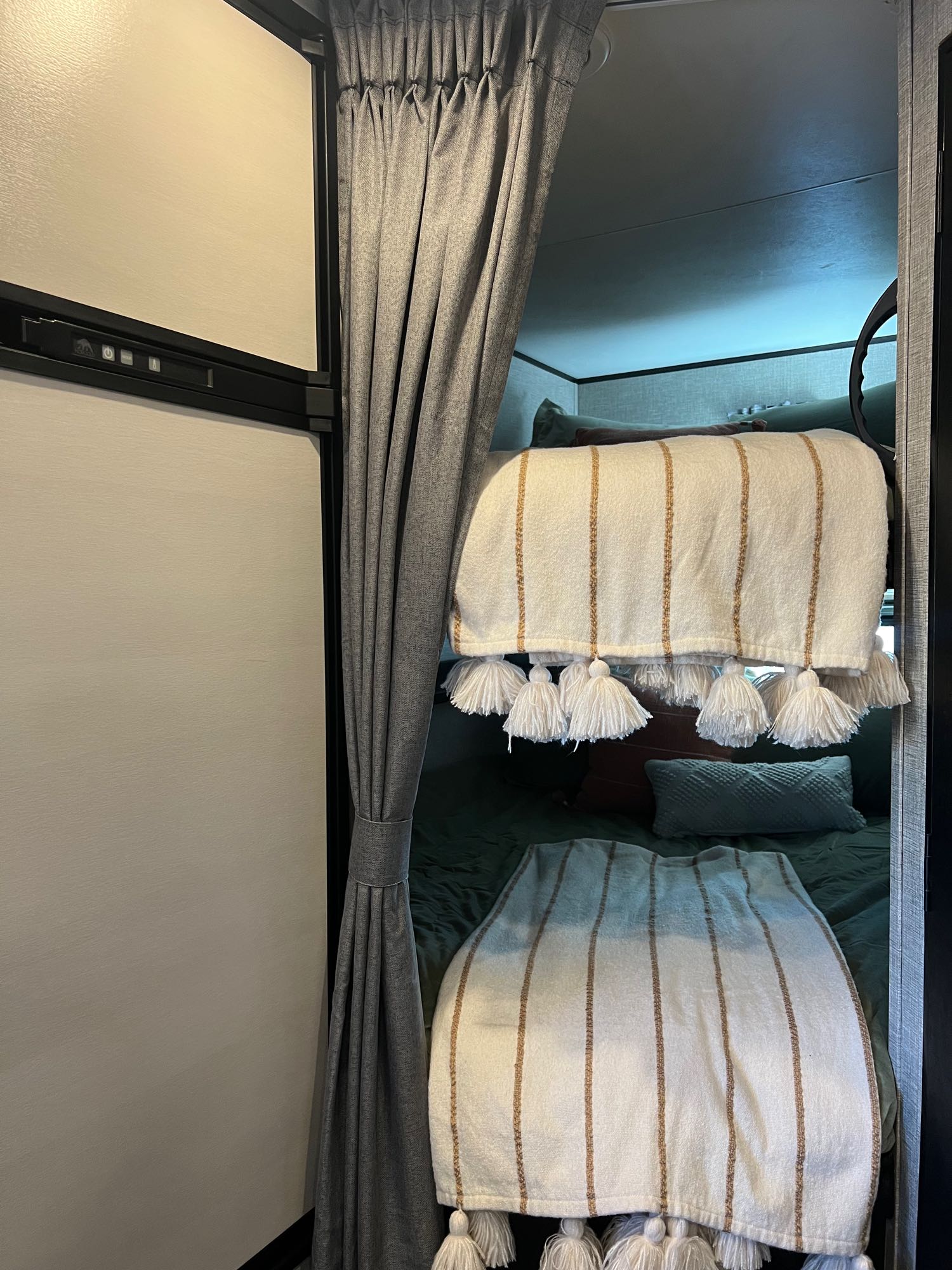 RV rental interior shows cozy bunk beds with throws and a refrigerator, offering comfortable camper living.. Jayco Featherlight SLX8 2022