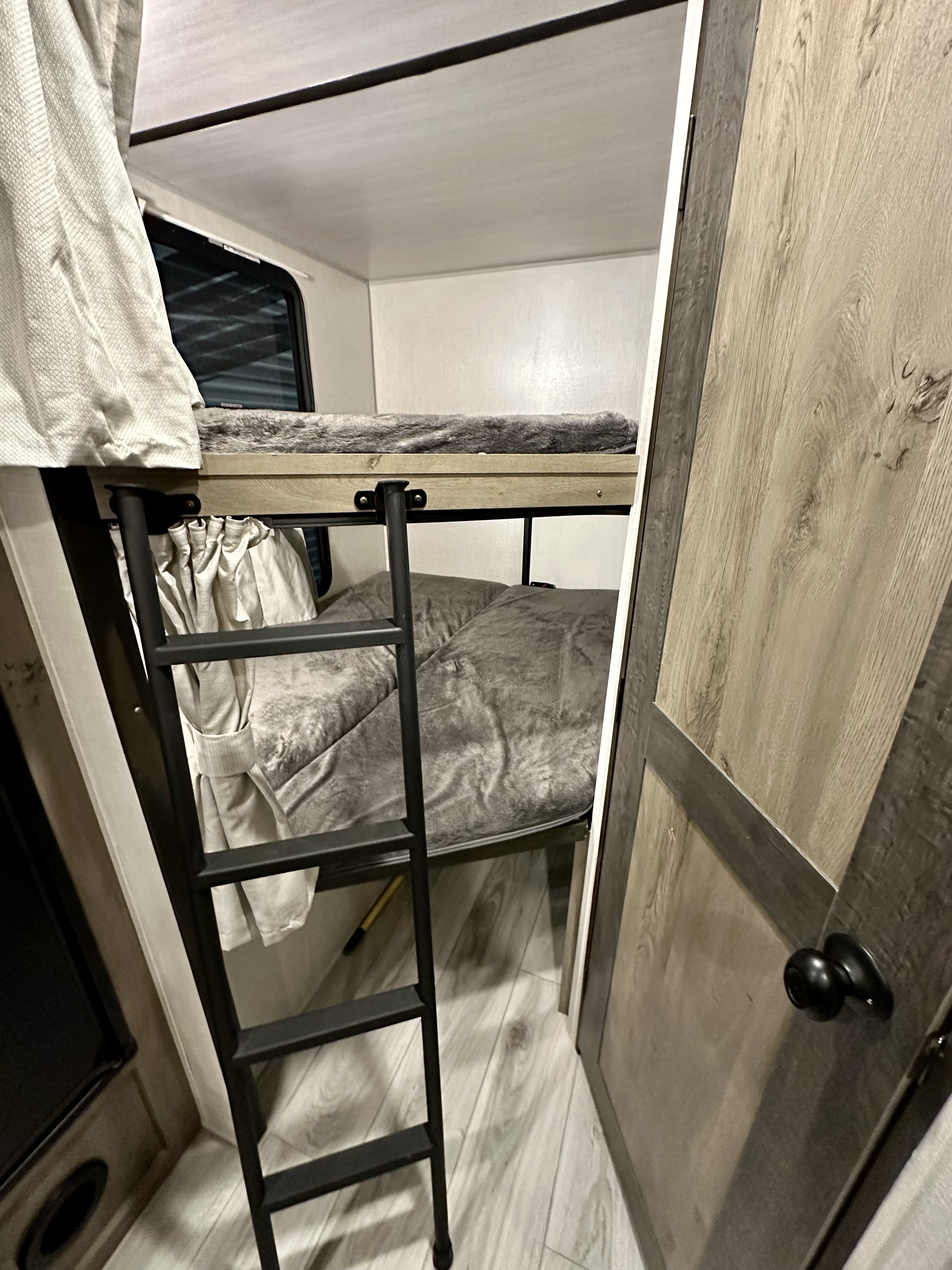 Inside an RV rental, showcasing comfortable bunk beds, a sturdy ladder, and a window for natural light. Ideal for family travel.. Forest River Other 2022