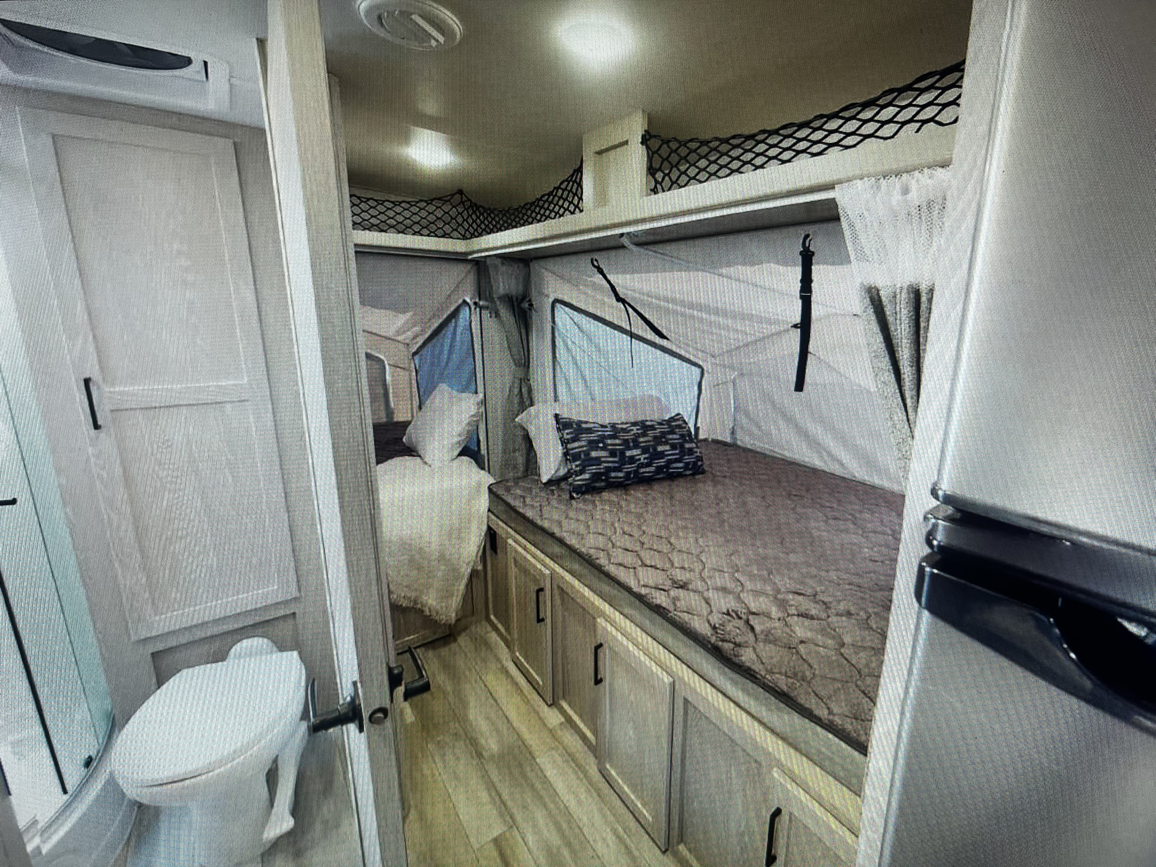 Inside an RV rental: a pop-out bed with mesh storage, a compact bathroom, and cabinet space, ready for your road trip.. Forest River Flagstaff Shamrock 2022