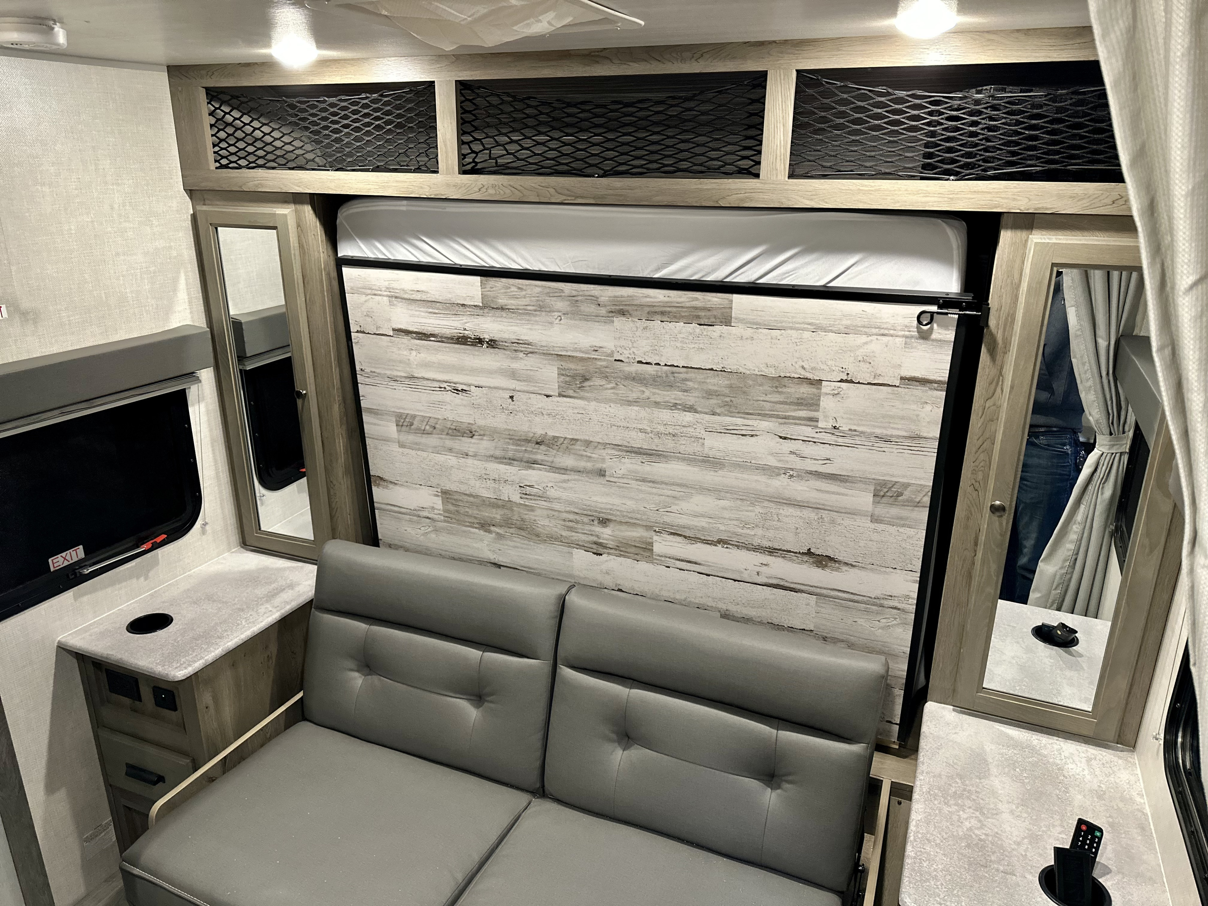 Compact RV rental interior featuring a clever pull-down Murphy bed, comfortable gray sofa, and overhead storage.. Forest River Other 2022