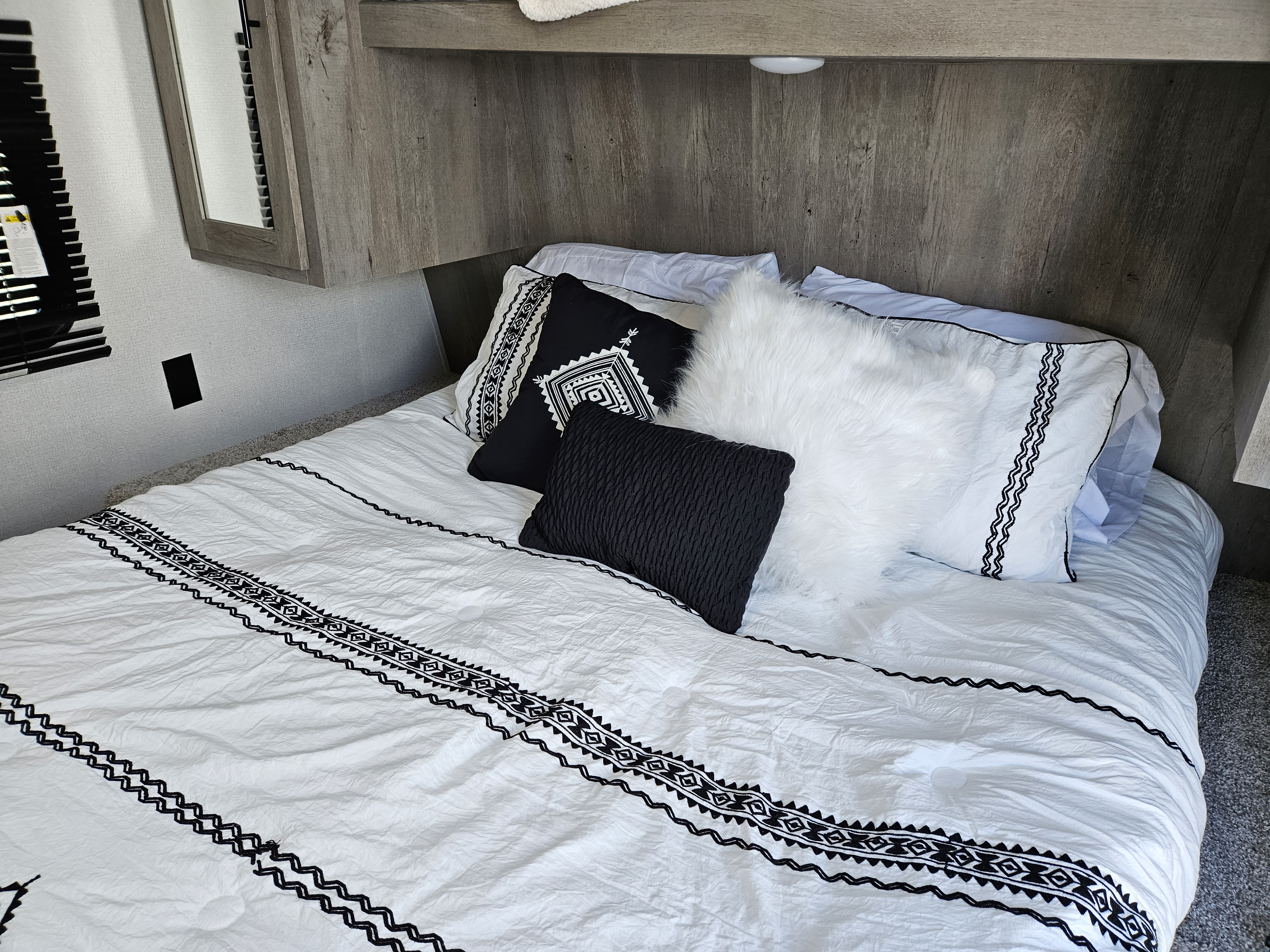 Stylish black & white RV rental interior featuring a cozy bed, perfect for your next adventure.. Keystone RV Springdale 2022