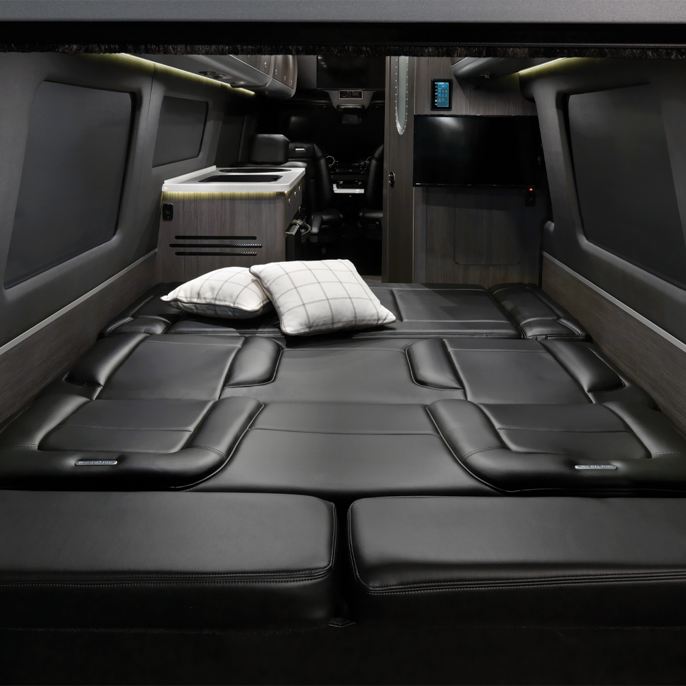 Spacious RV rental interior with a large black leather bed, kitchenette, and entertainment system.. Airstream Interstate 2021