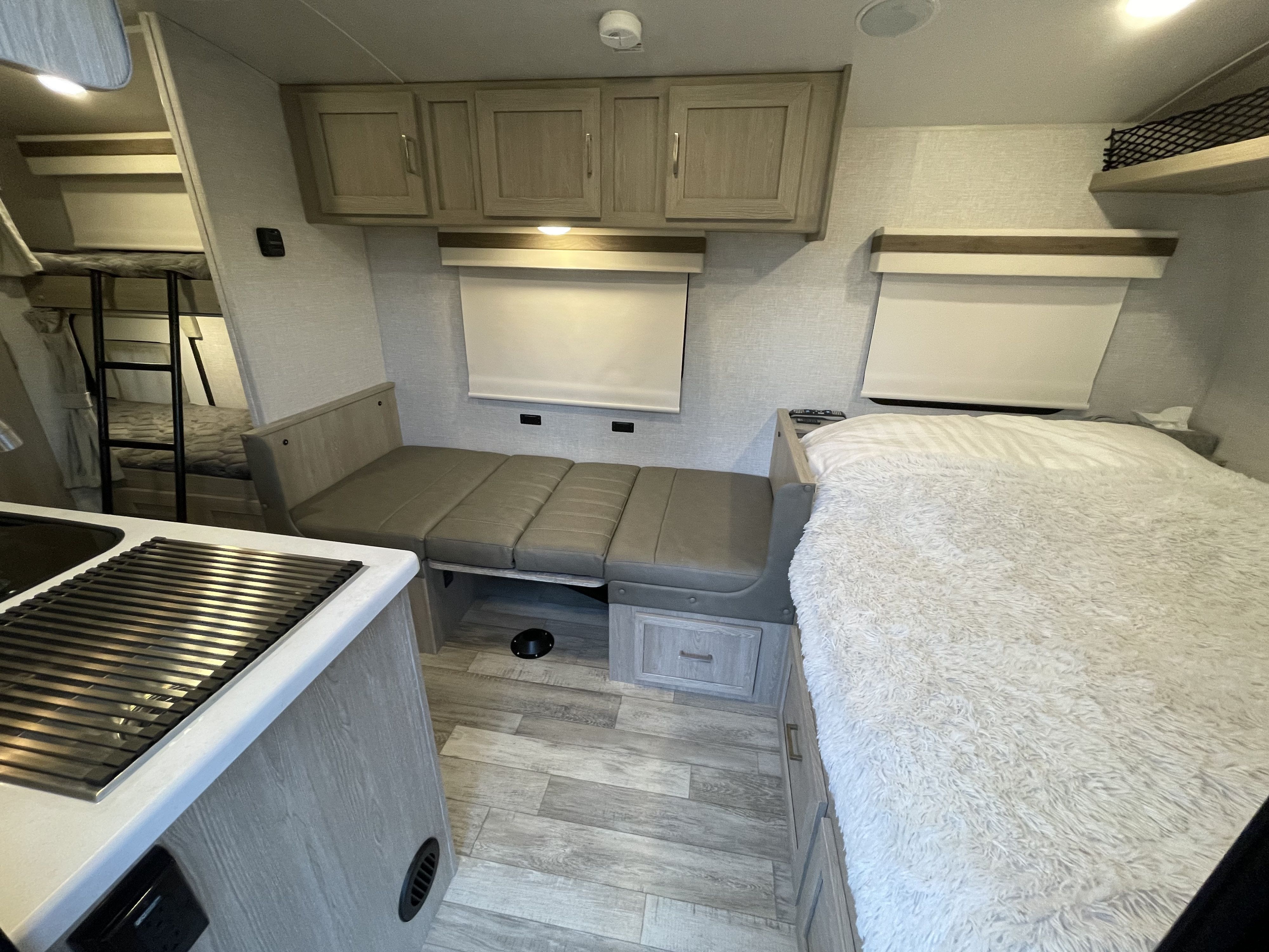 RV rental interior showcasing bunk beds, a convertible dinette, main bed, and compact kitchen amenities.. Forest River Rockwood Geo Pro 2022