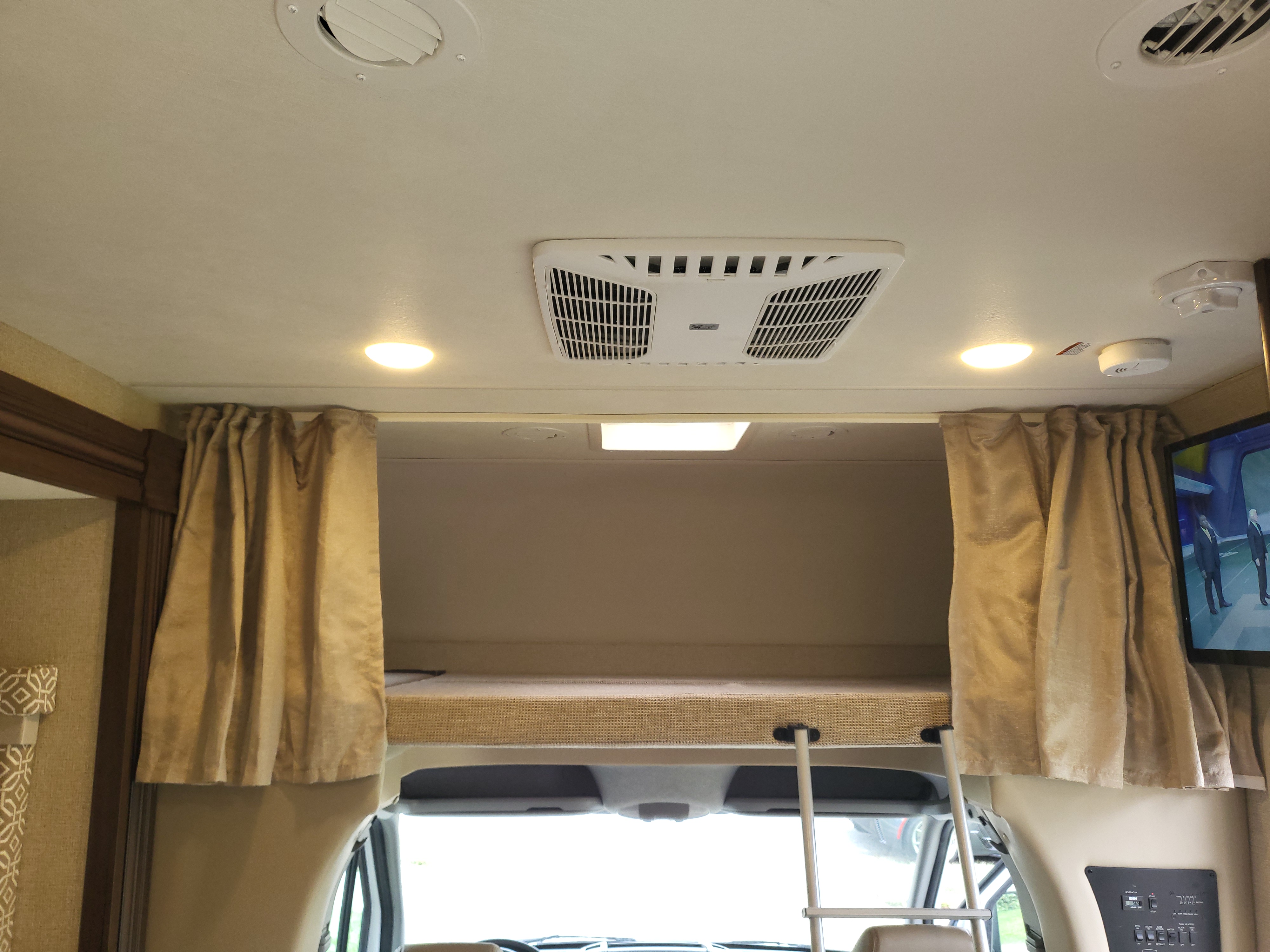 RV rental: Interior view of the over-cab bunk bed with ladder, curtains, AC, lights, and control panel for guests.. Thor Freedom Elite 2018
