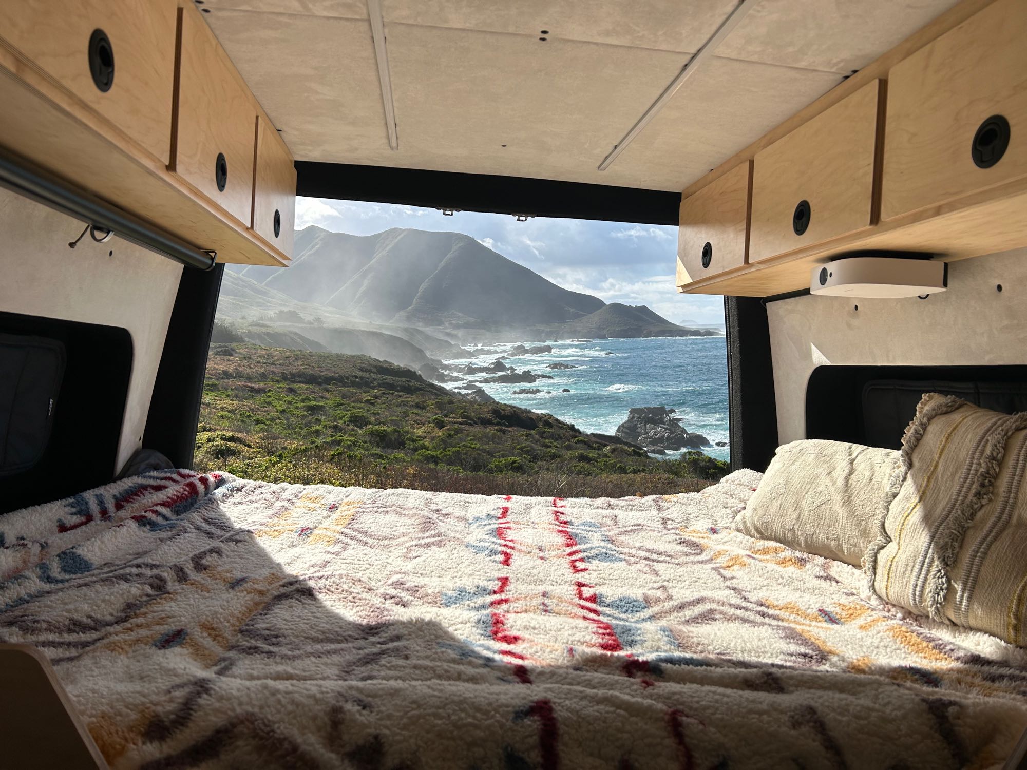 A cozy RV rental bed offers stunning ocean, coastline, & mountain views from inside this camper van.. Mercedes-Benz Sprinter RV Motorhome Campervan 2022