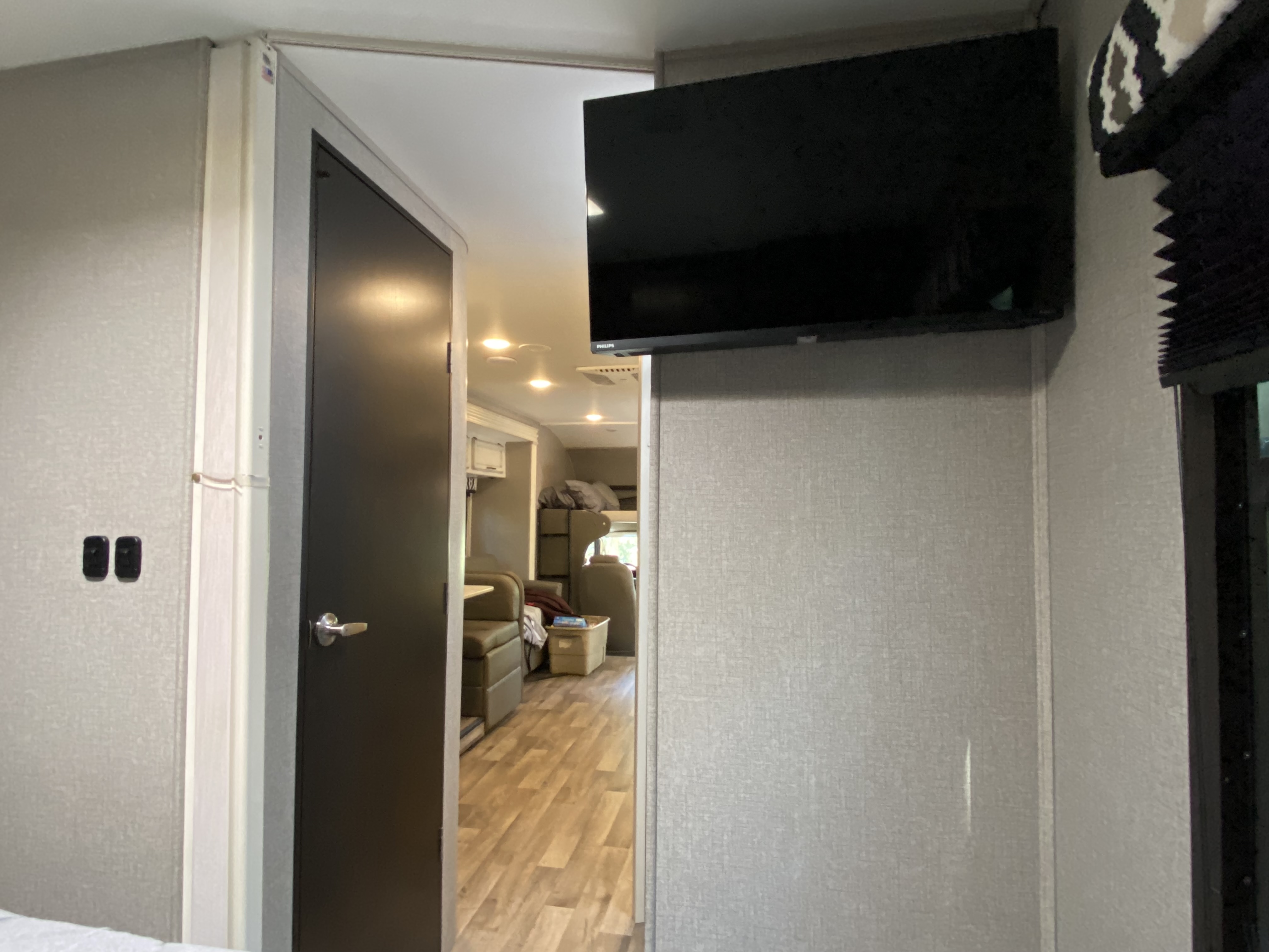 RV rental interior. A door reveals the living space, bunk beds, and mounted TV, showcasing comfort.. Jayco Redhawk 2021