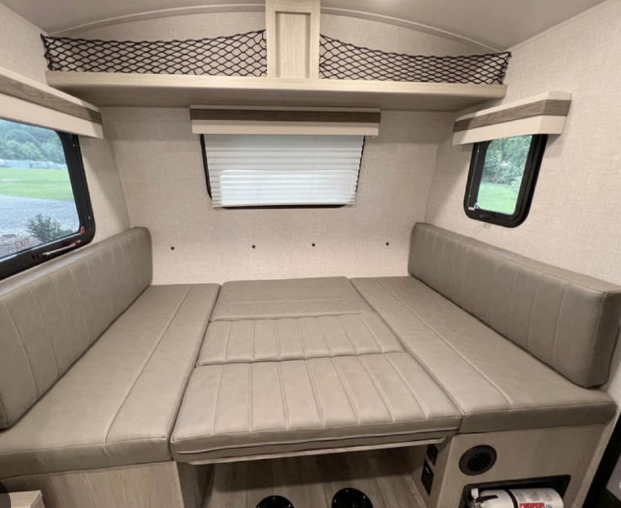 RV rental: Interior shows a flexible bed/seating area formed by light grey cushions, side windows, and overhead net storage.. Forest River Geo Pro 19BH (bunk house) 2023