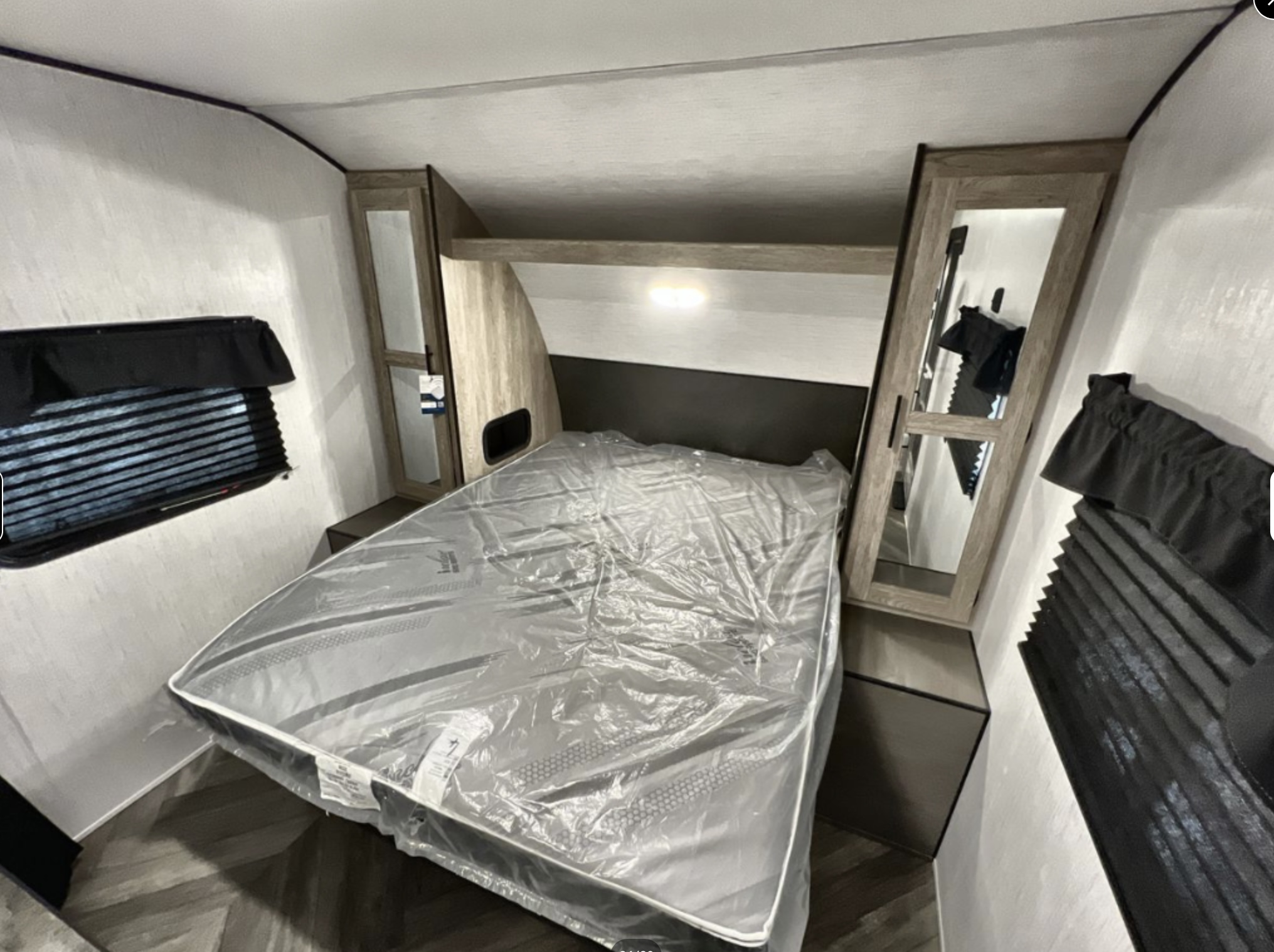 Compact RV rental bedroom featuring a new mattress, overhead storage, and windows with blinds. Ideal for travel.. Heartland Prowler 2023