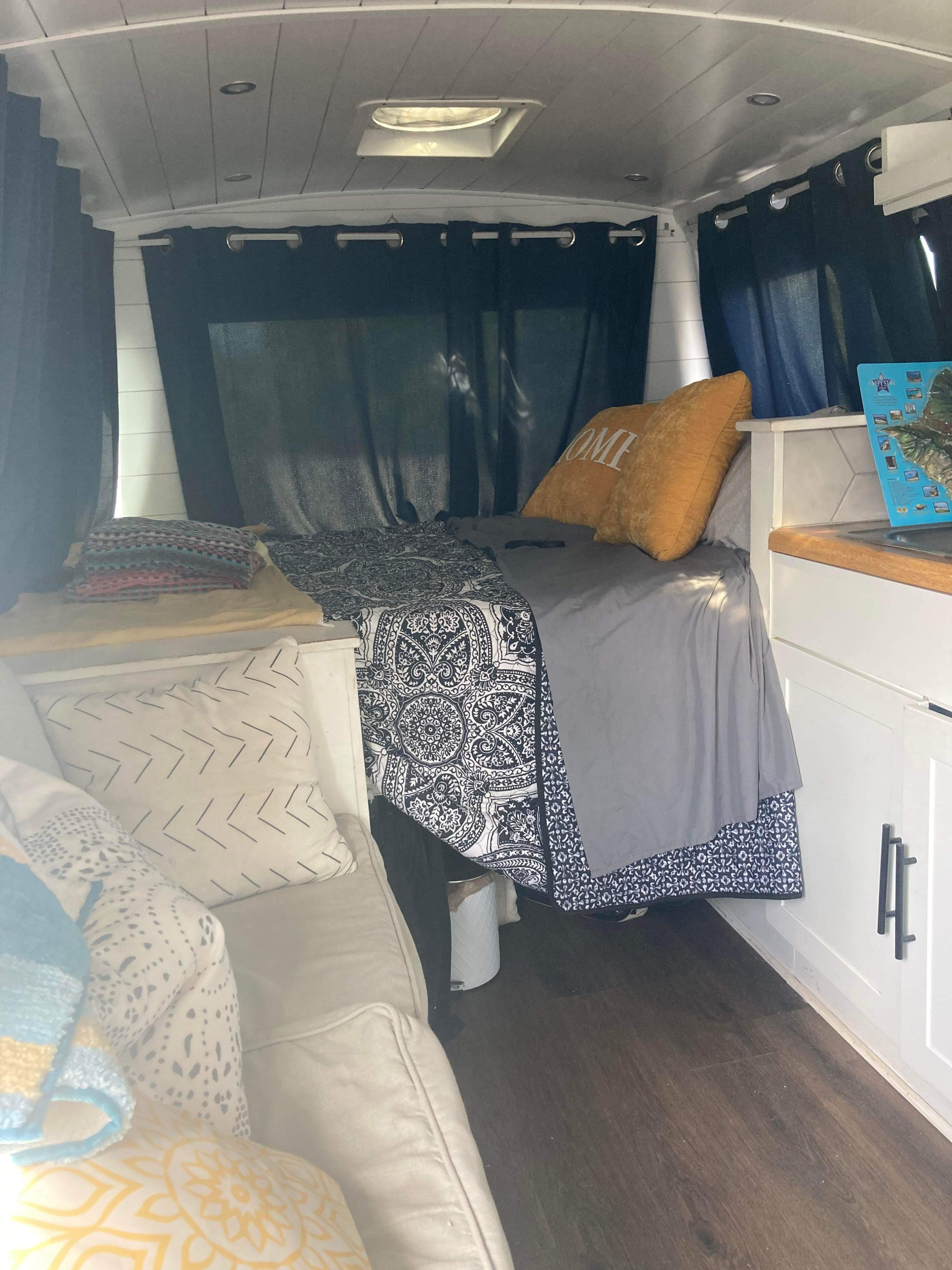 Cozy RV rental interior with a bed, couch, and small kitchenette area, perfect for a comfortable road trip.. Ford Real Lite Econoline 350 2014