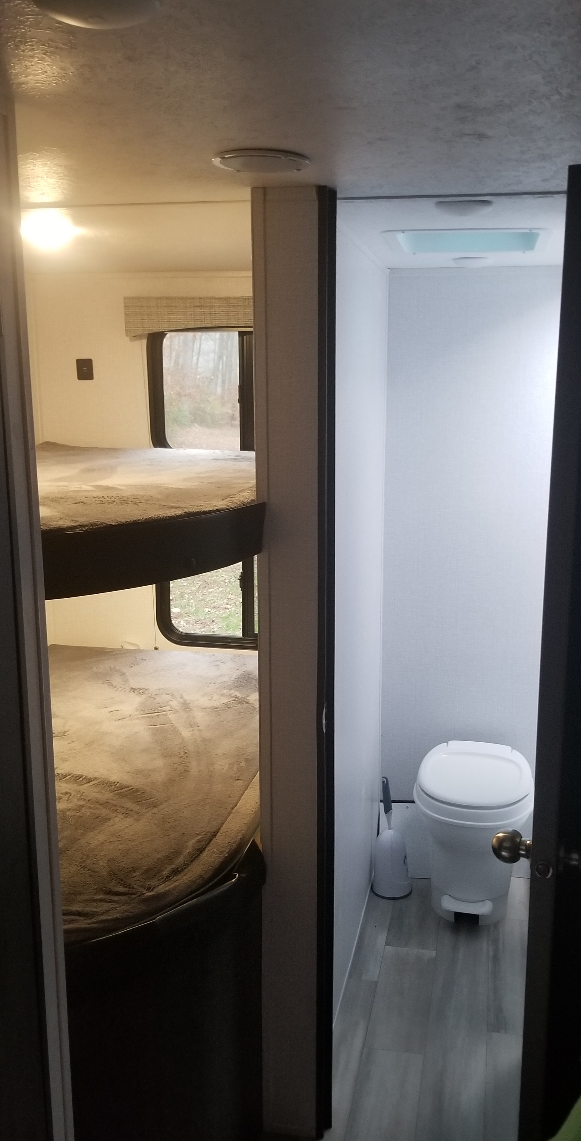RV rental interior: A cozy bunk bed area is on the left, with a compact bathroom and toilet visible on the right. Perfect for camping adventures.. Coachmen Clipper 2022