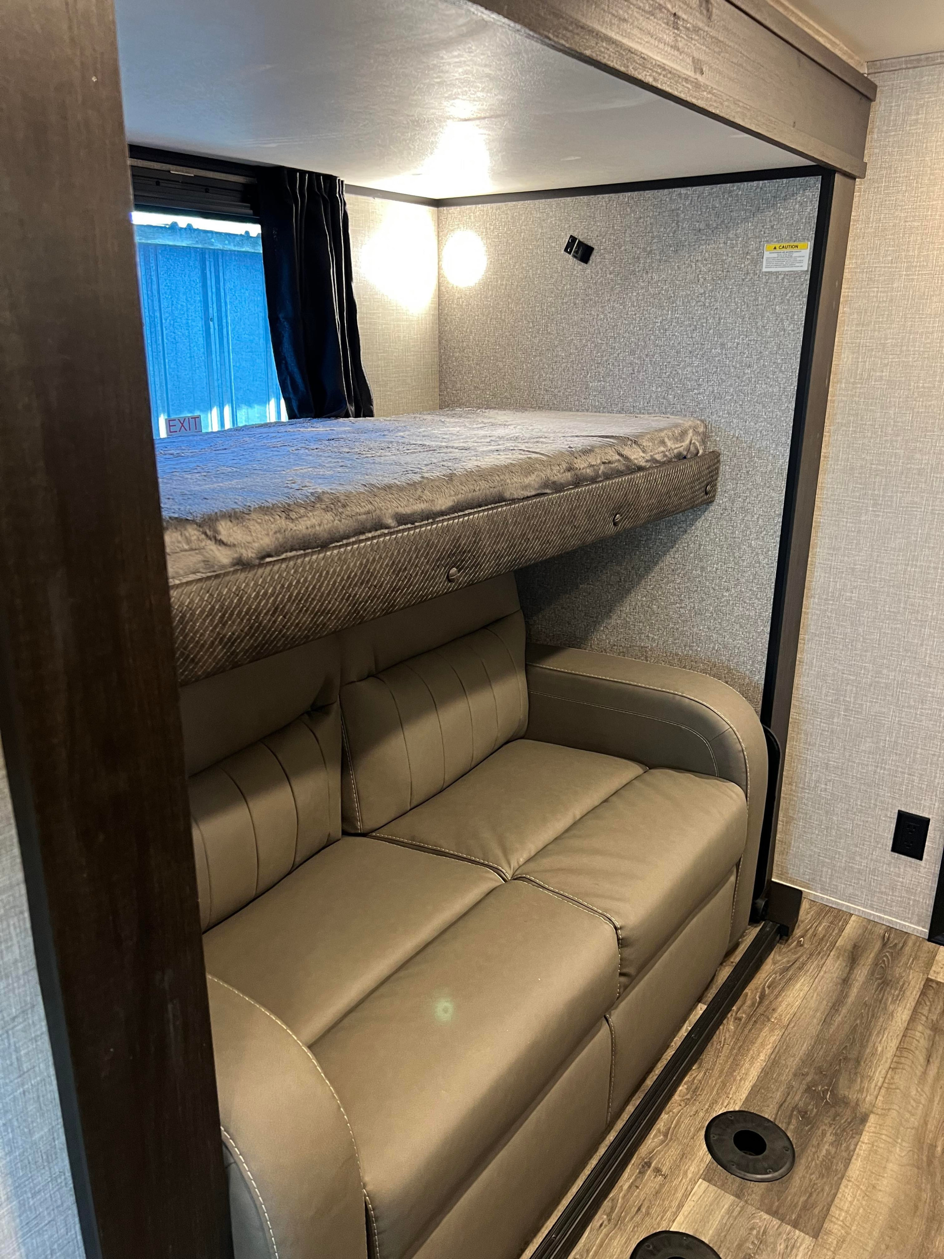 Modern RV rental interior showcasing a space-saving bunk bed over a comfortable sofa, ideal for travelers.. Jayco North Point 2022