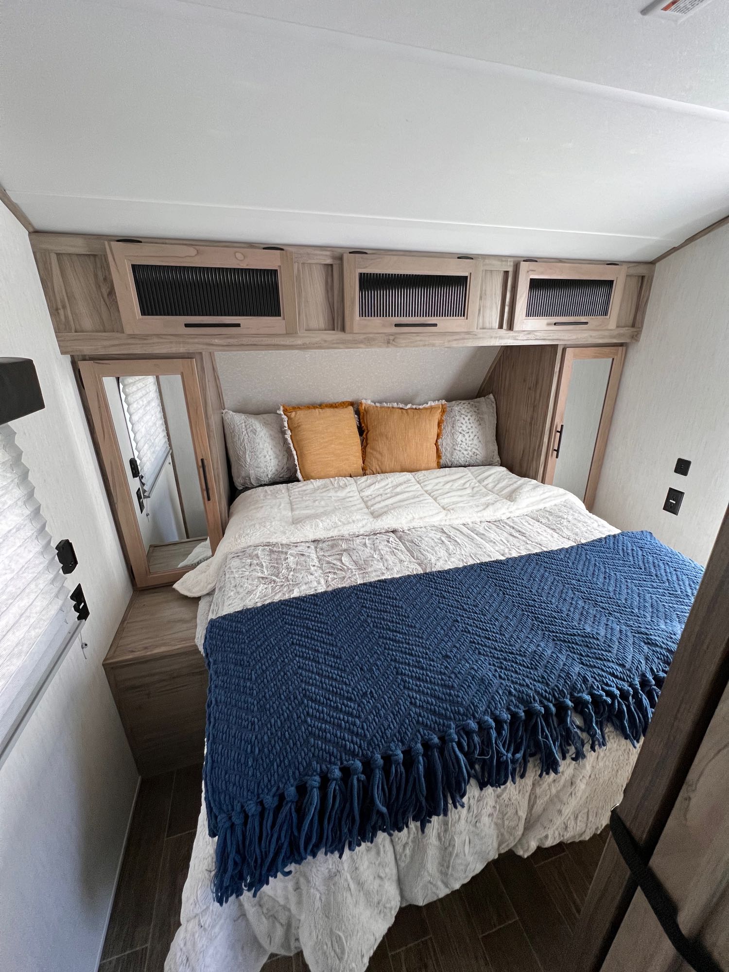 Explore this inviting RV rental bedroom. It boasts a comfy bed, overhead cabinets, and mirrors.. Forest River Cherokee 2021