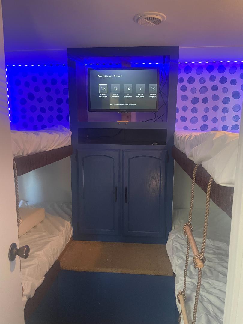 RV rental bunk room with blue LED lights, TV, and two beds. Cozy setup for family adventures.. Forest River Wildwood 2010
