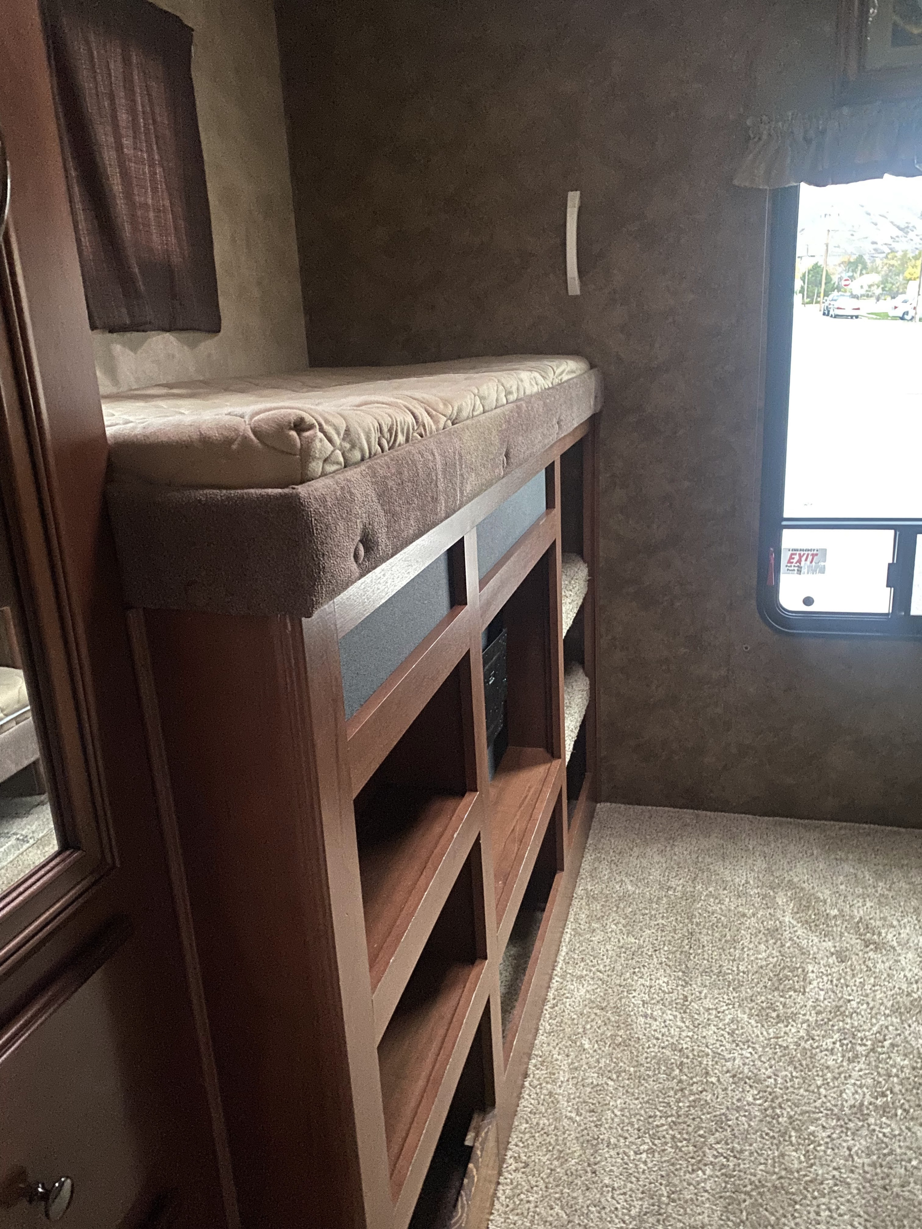 View inside an RV rental, showing a cozy bunk bed, ample storage, and a large window for natural light.. Forest River Sandpiper 2013