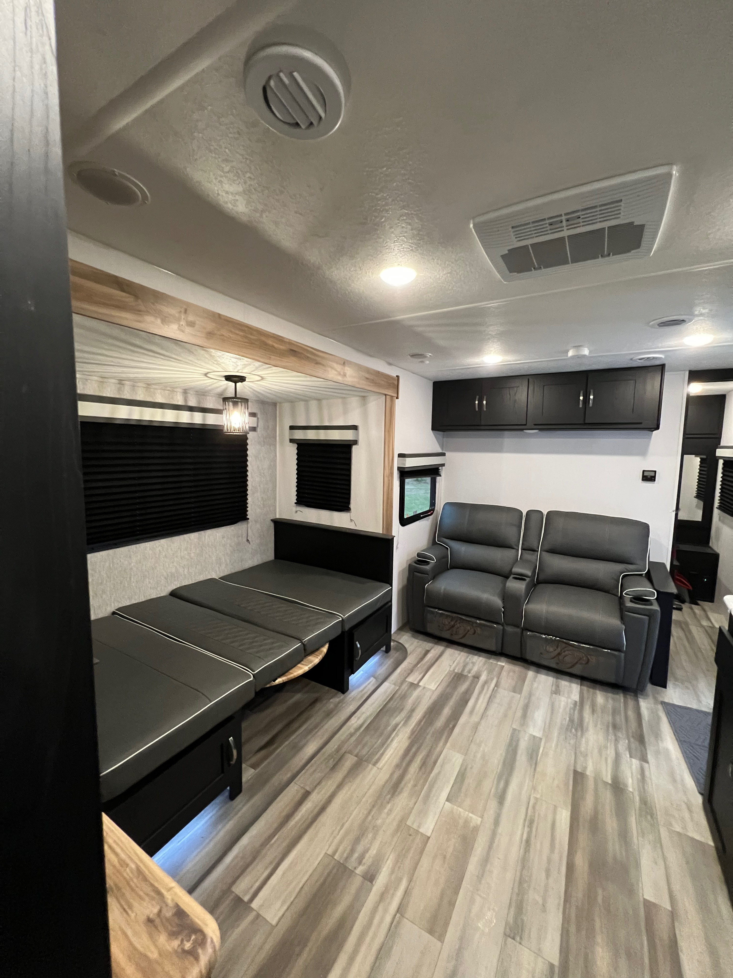 Spacious modern RV rental interior featuring gray flooring, a convertible dinette, and reclining seats with black accents.. Coachmen Freedom Express 2022