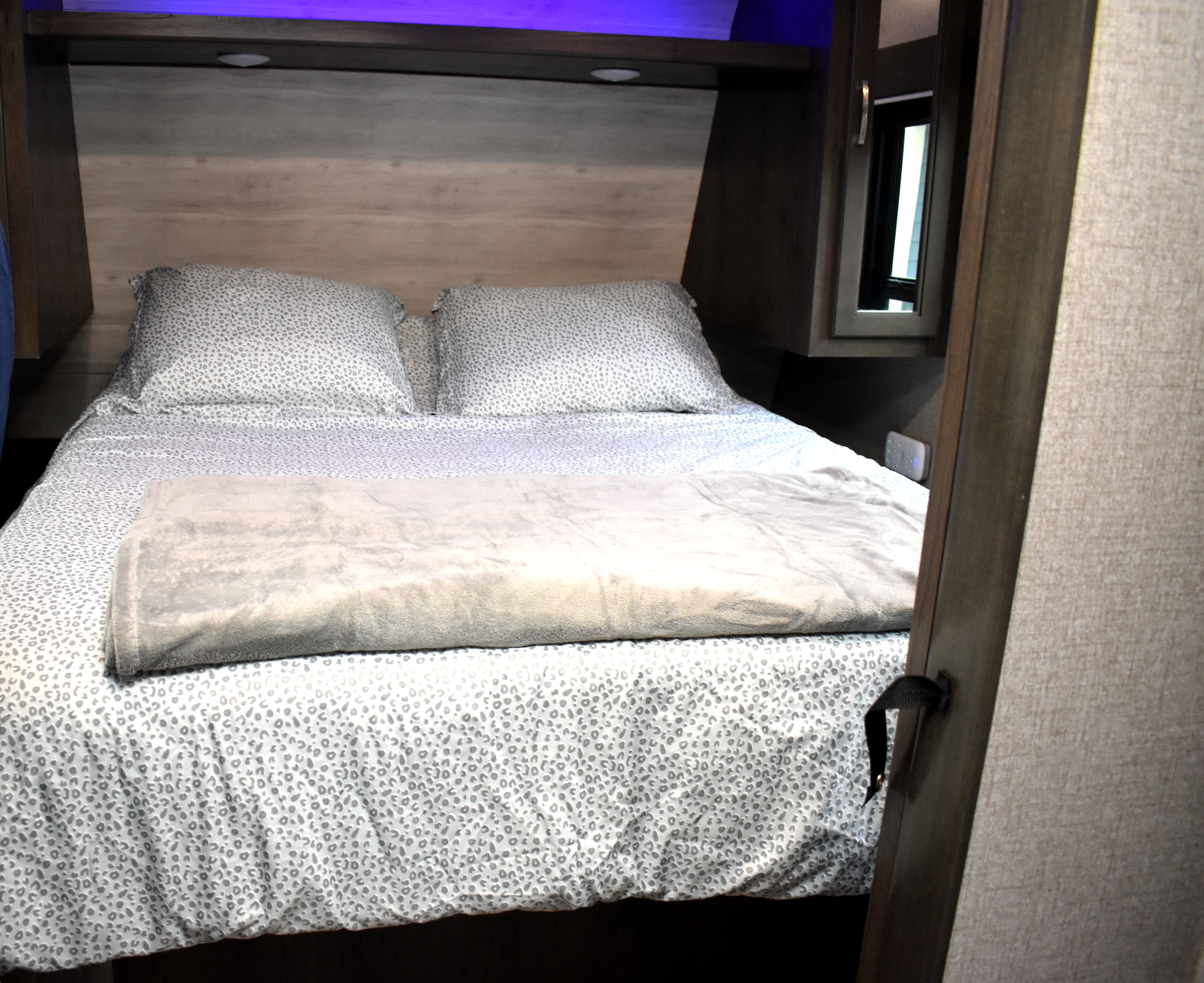 RV rental's comfy bedroom featuring patterned sheets, a soft blanket, and overhead lighting/storage for a relaxing stay.. Jayco Jay Flight SLX Rocky Mountain Edition 2021