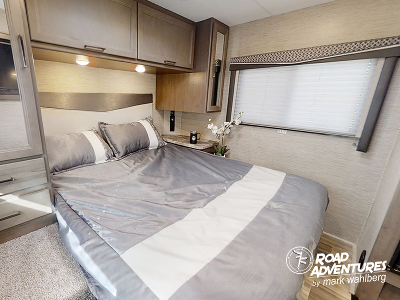 Cozy RV rental bedroom with a comfortable bed, overhead cabinets, and a window. Perfect for your next road trip.. Thor Motor Coach Four Winds 28Z 2024