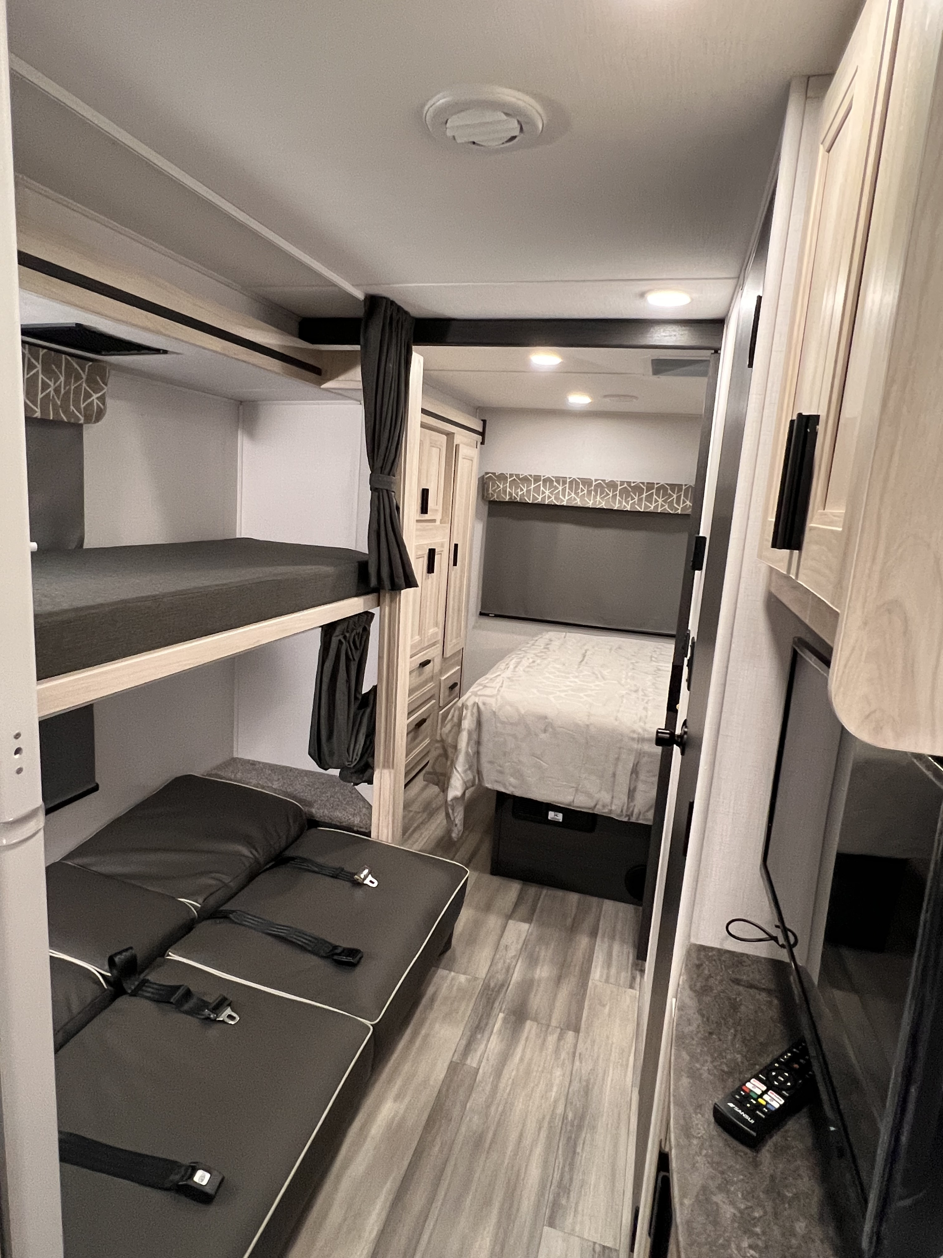 Inside a modern RV rental featuring comfortable bunk beds, a main bed, flexible seating with seatbelts, and cabinets.. Forest River Sunseeker 2024
