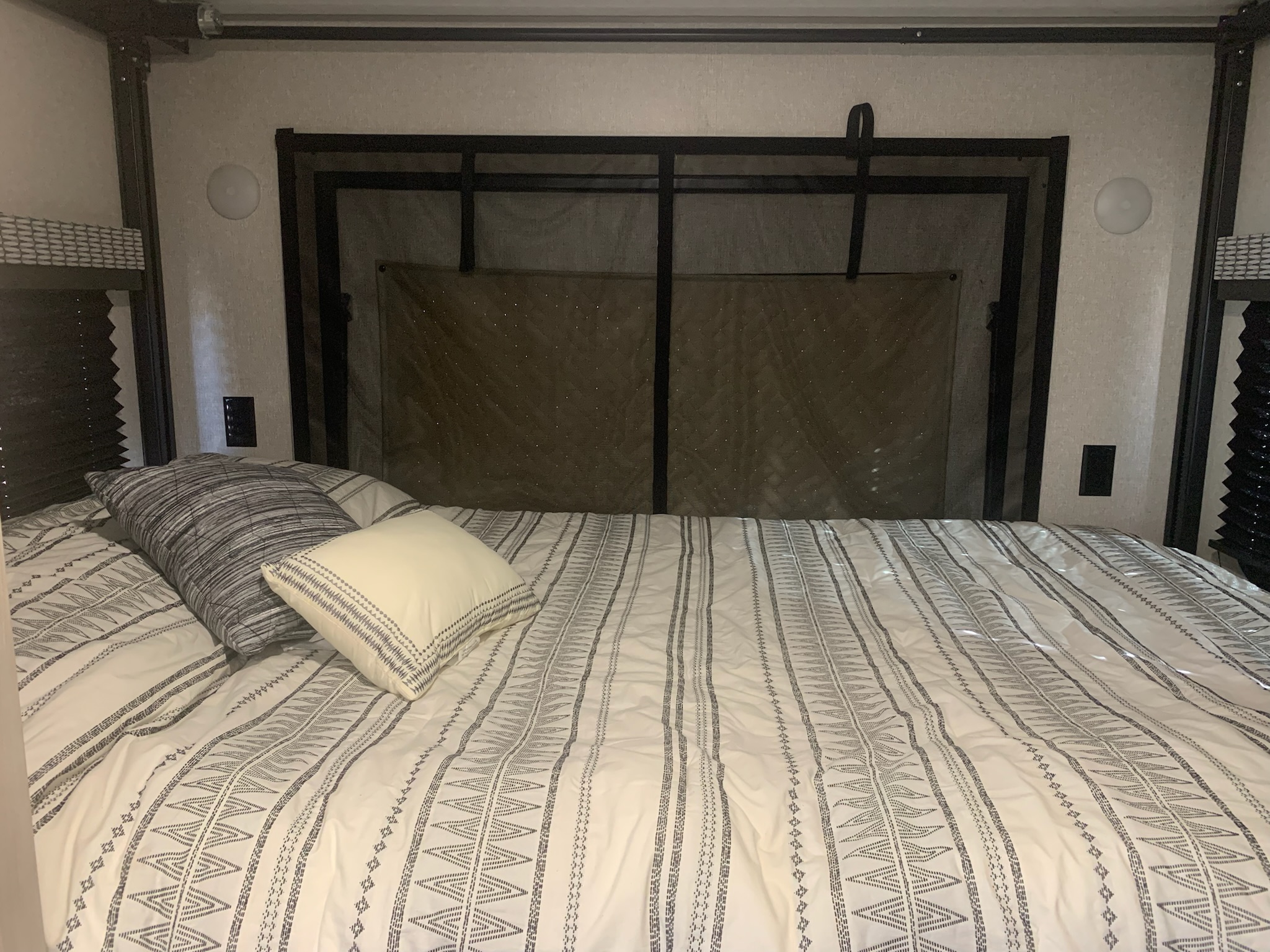 Cozy RV rental bedroom featuring patterned bedding, pillows, and a mesh headboard for comfortable rest.. KZ Other 2022