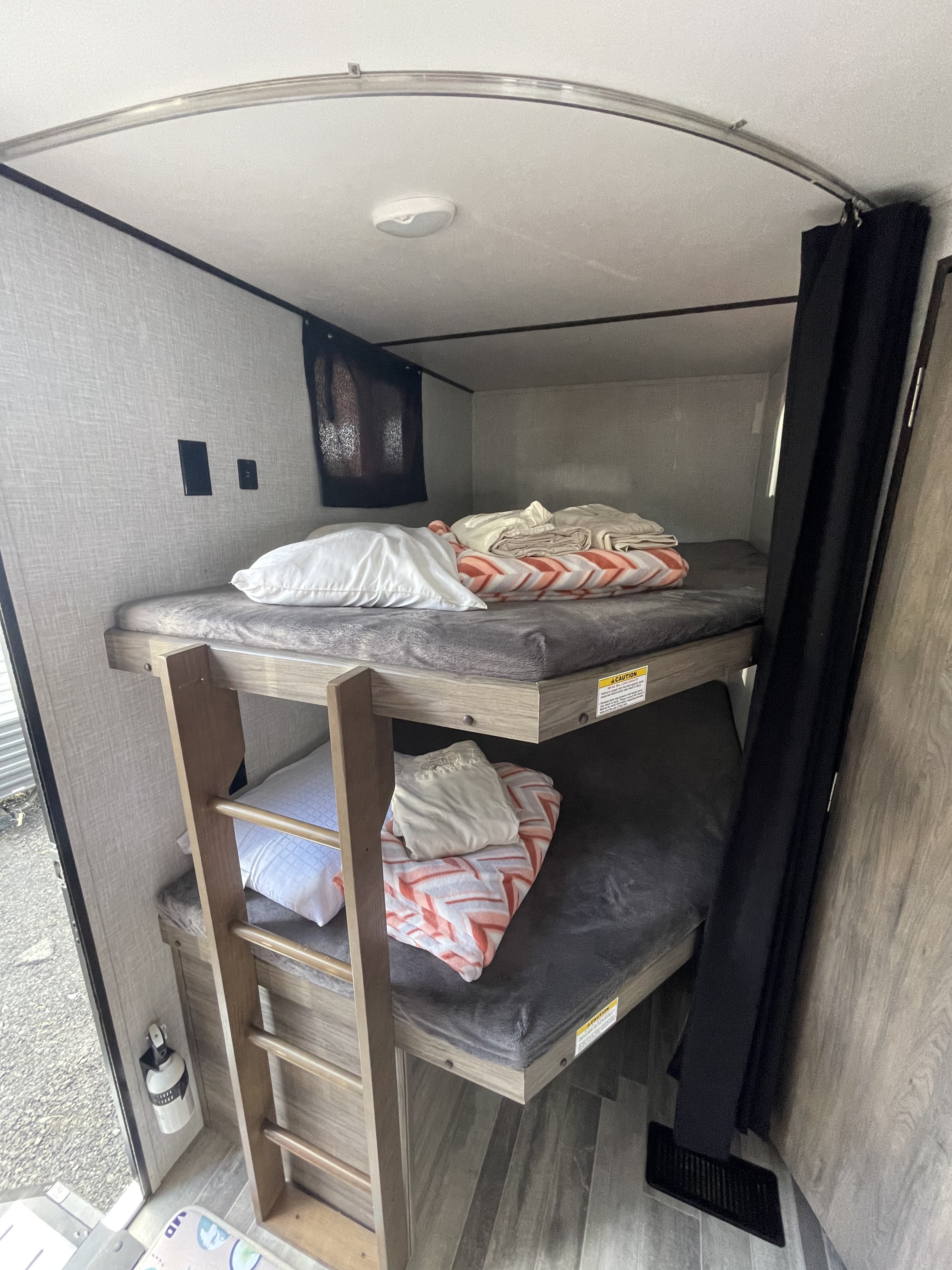 RV rental: Stacked bunk beds with mattresses, pillows, and blankets. Features include a ladder, ceiling light, and wall outlets.. Crossroads RV Zinger Lite 2021