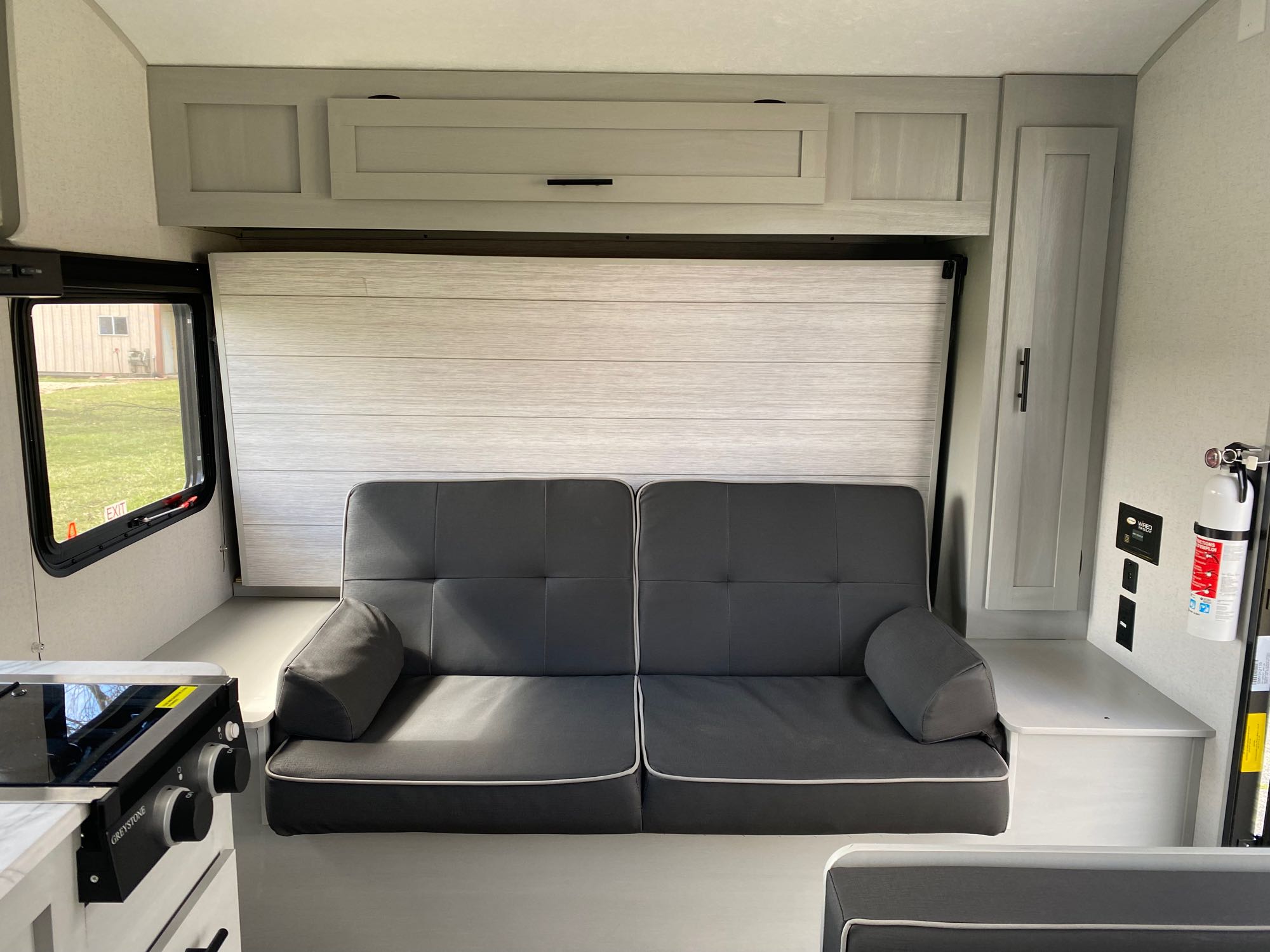 This RV rental features a gray convertible sofa, overhead storage, and a compact kitchen stove, optimizing interior space.. Forest River Salem 2022