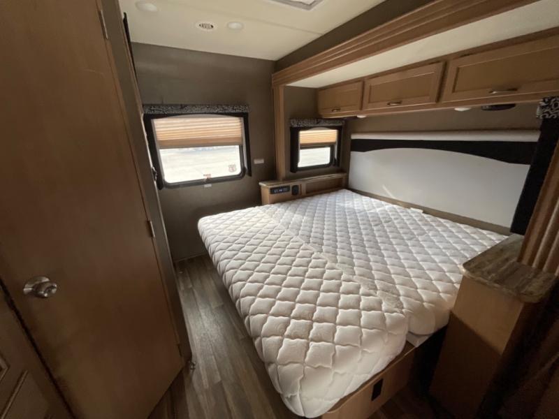 Spacious RV rental bedroom featuring a comfy queen bed, overhead cabinets, and windows. Ready for your next adventure!. Thor A.C.E. 2018