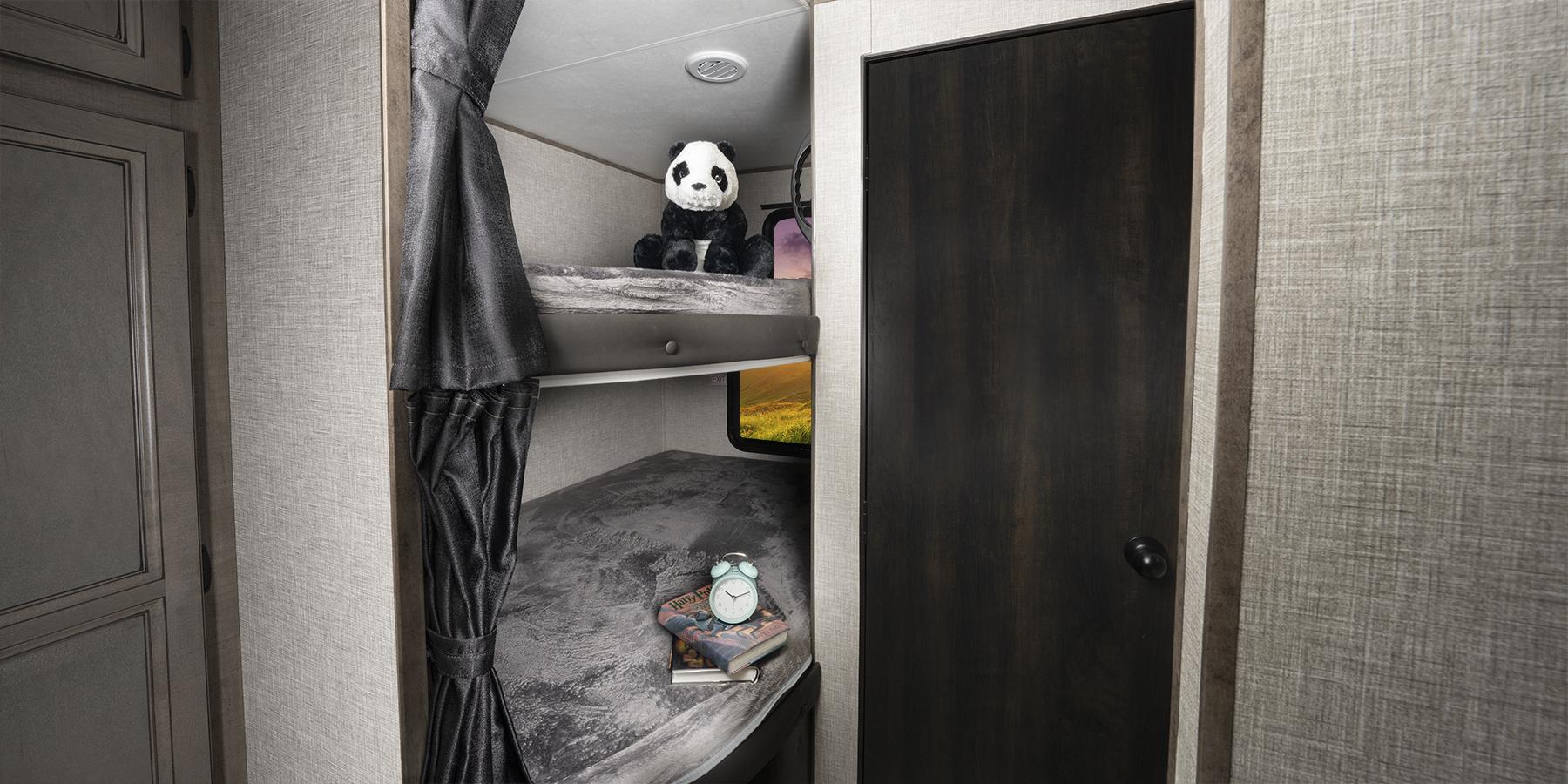 RV rental interior features cozy bunk beds. Panda on top bunk, books & alarm clock on lower bunk – perfect for family travel.. Jayco Jay Flight SLX 2023