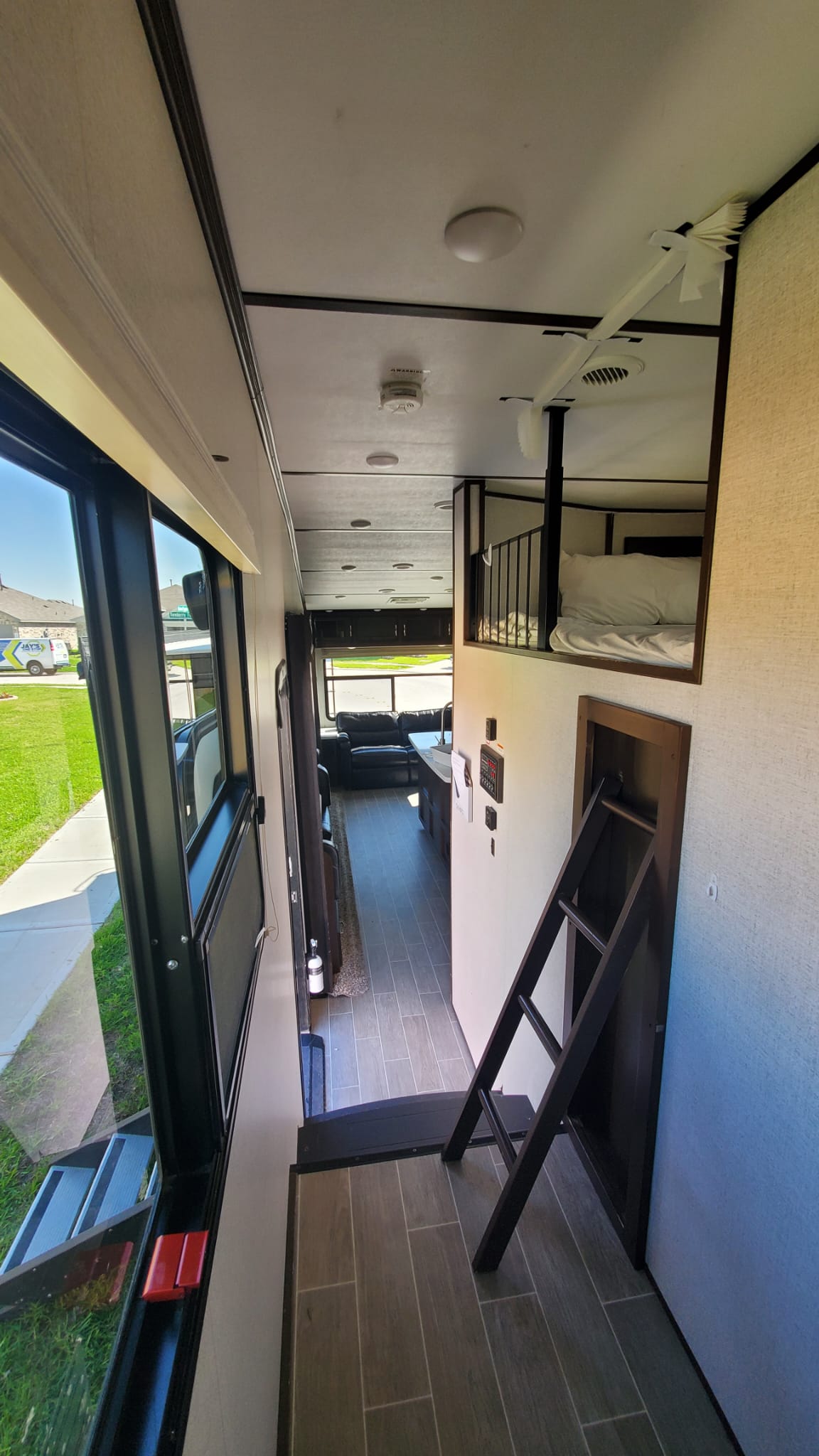 Spacious RV rental interior featuring a cozy loft bed with ladder access, living area, and large windows.. Atlas Atlas Fifth Wheel 2020