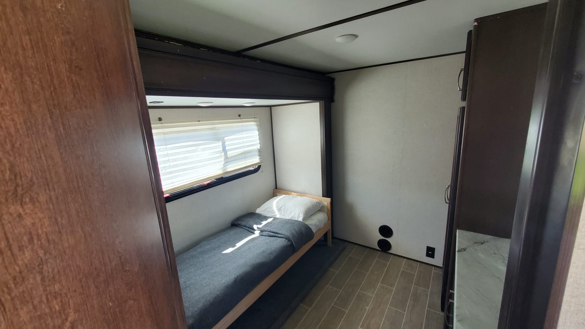 Explore this RV rental's cozy bunkhouse: a single bed, window, and wood-look flooring. Ideal for extra sleeping.. Atlas Atlas Fifth Wheel 2020