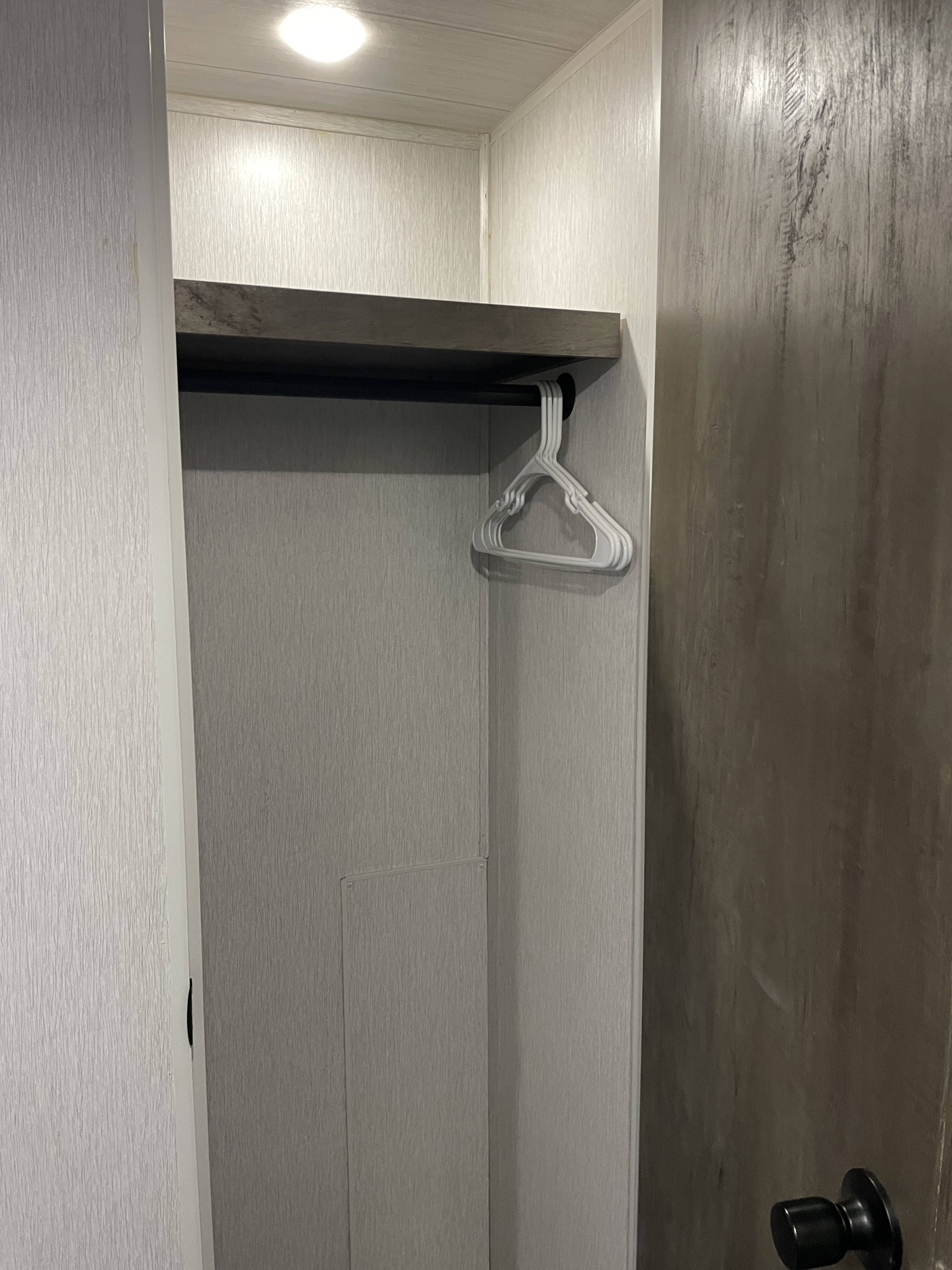 RV rental's functional closet: overhead light, shelf, and hanging rod with hangers. Optimized storage for small spaces.. Forest River Salem 2022