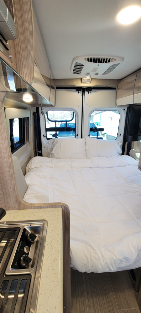 Cozy RV rental campervan interior features a comfy bed, windows, and a compact kitchen for your adventures.. Thor Motor Coach Sequence 2023