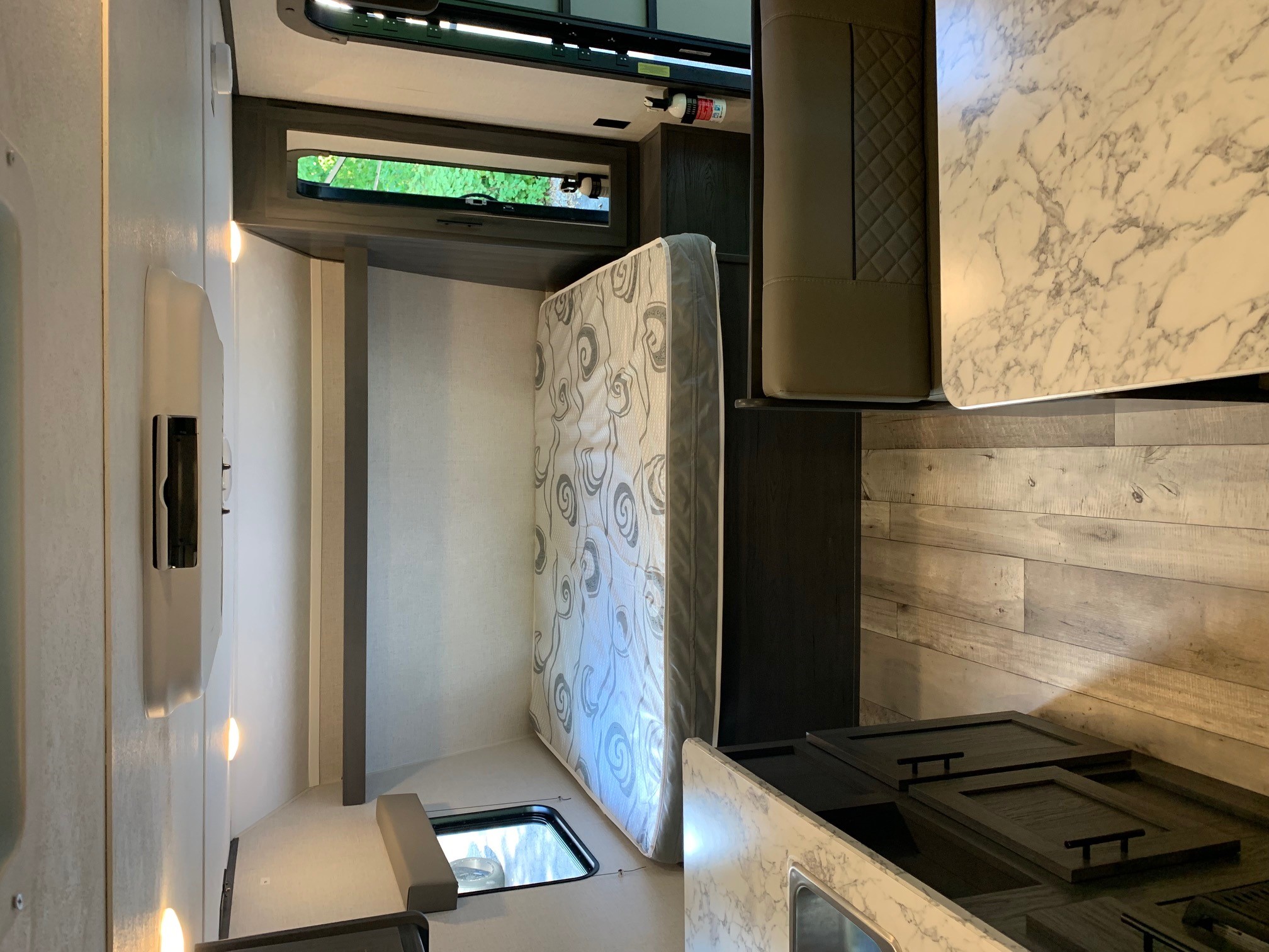 An rv rental's interior shows a versatile living space with an upright mattress, dining table, and kitchen area.. Aspen Trail LE 2021