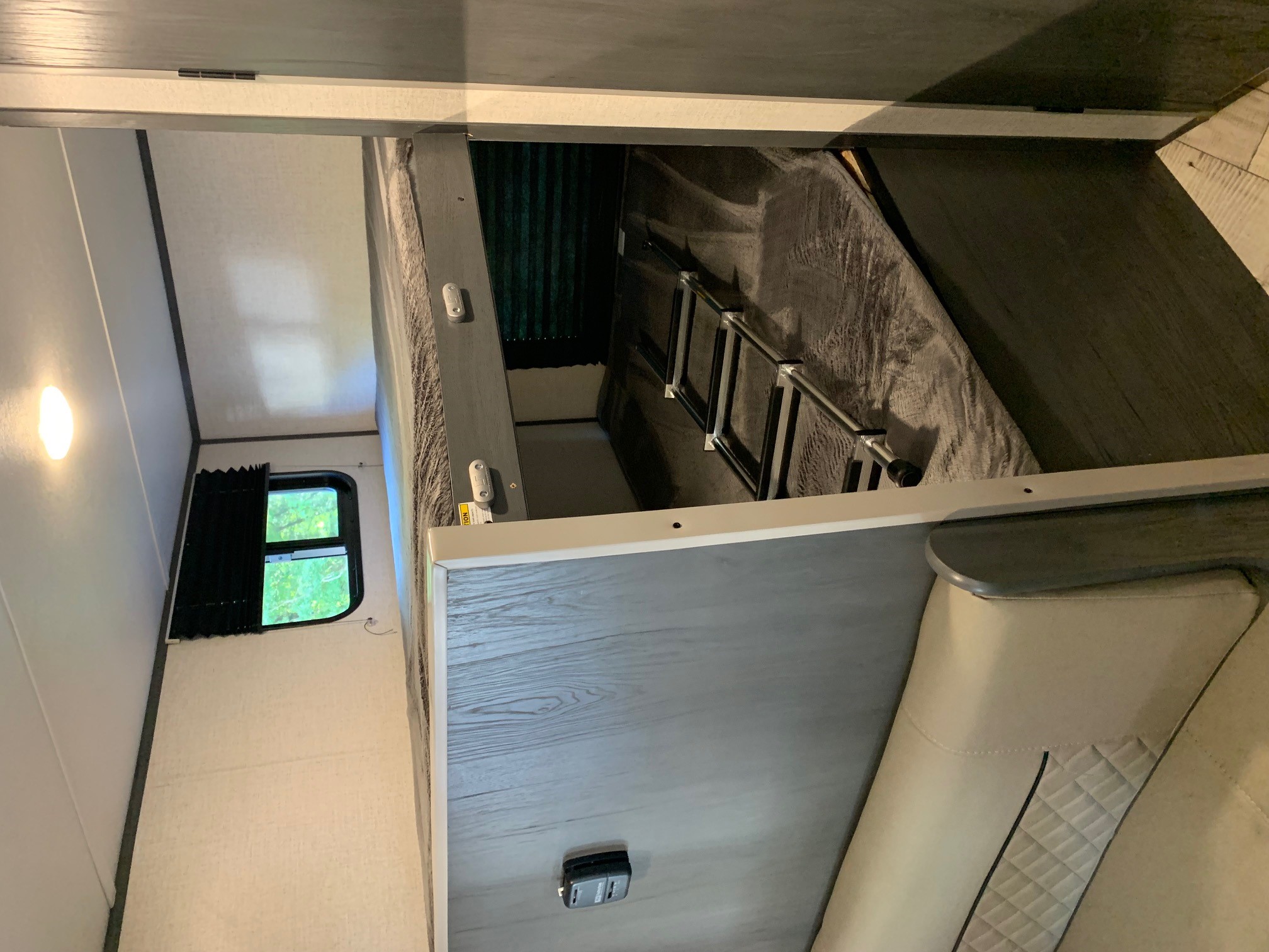 Cozy RV rental interior featuring bunk beds with a ladder, a window, and a comfortable dinette, ideal for family trips.. Aspen Trail LE 2021