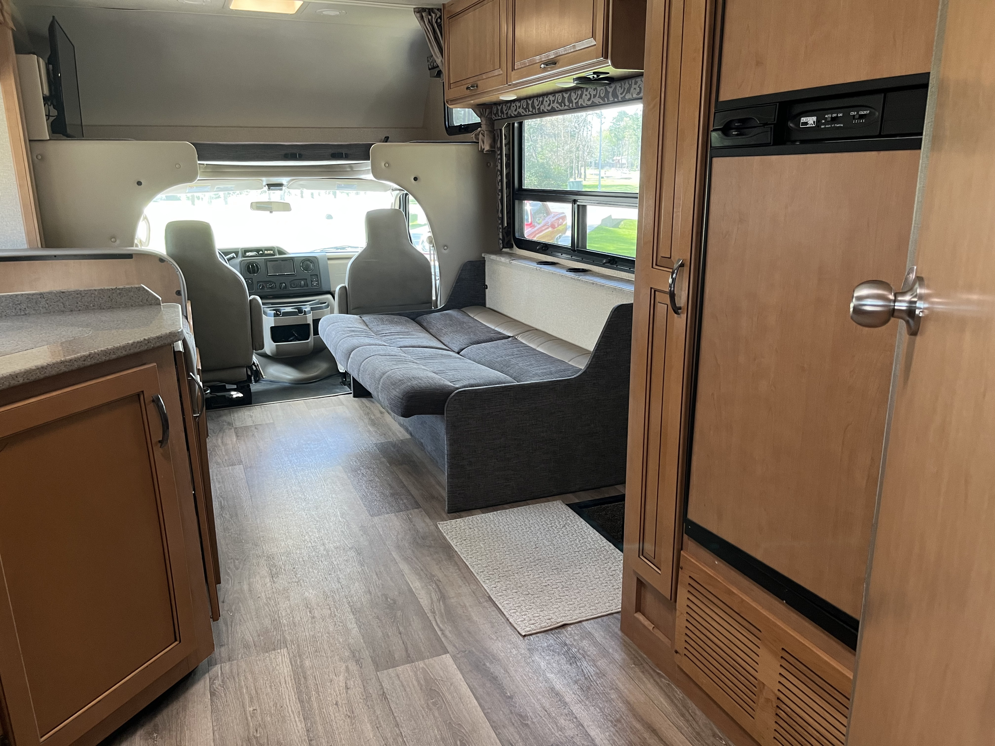 Spacious RV rental interior showcasing the cockpit, sofa bed, kitchen counter, and overhead bunk area.. Thor Four Winds 2017
