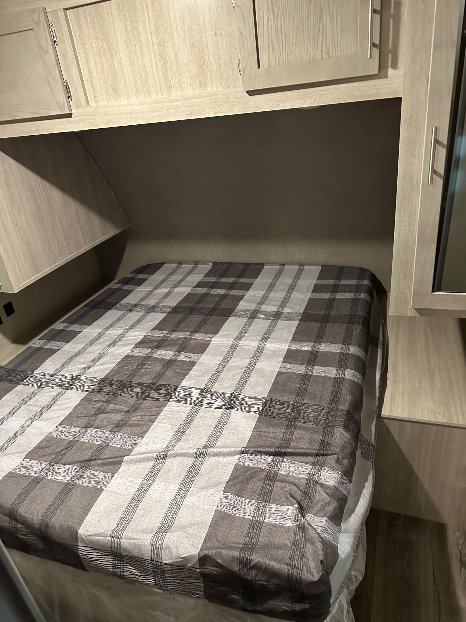 RV rental bedroom with a comfy plaid bed, light wood overhead cabinets, and built-in storage.. Coachmen 293QBCK 2022
