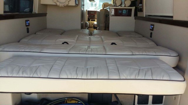 This RV rental offers comfortable, versatile two-tier white upholstered beds/seating, with controls visible for travel.. Midwest Automotive Designs Midwest Automotive Designs Class B 2017