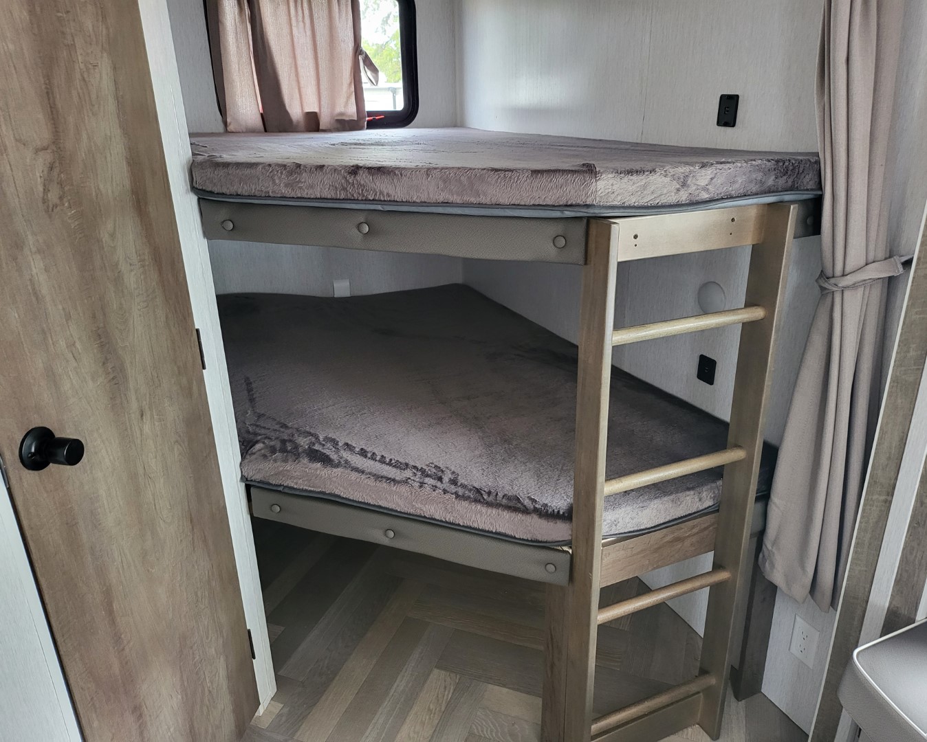 Cozy RV rental bunk beds with soft gray blankets and a wooden ladder. Compact sleeping area for your next adventure.. Forest River Salem 2022