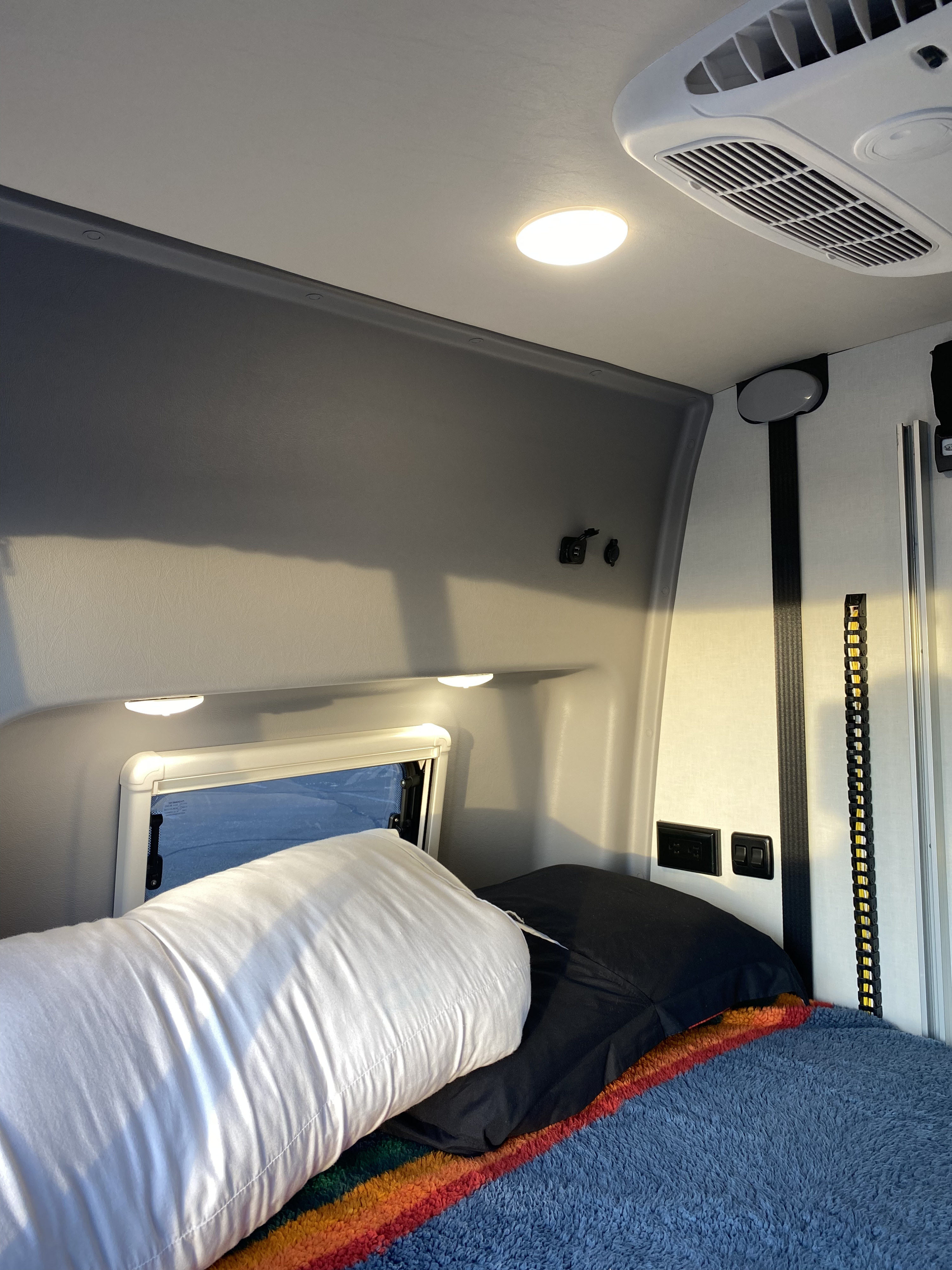 Main sleeping area with USB reading lights as well as a window . Winnebago Revel 2021
