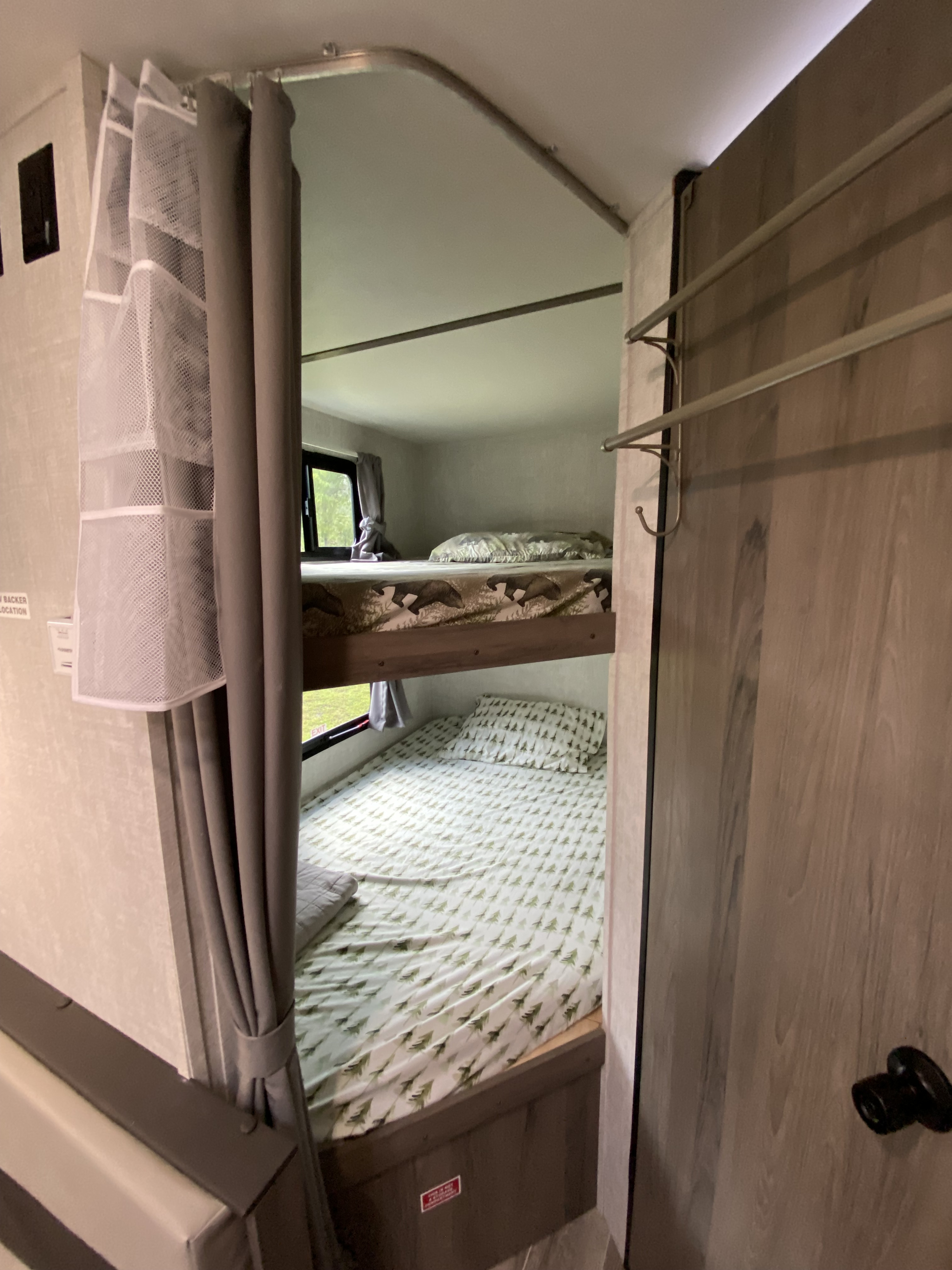 Inside an RV rental, two bunk beds with patterned bedding (bears and trees), a window, and privacy curtain.. Gulf Stream Ameri-Lite Super Lite 2021