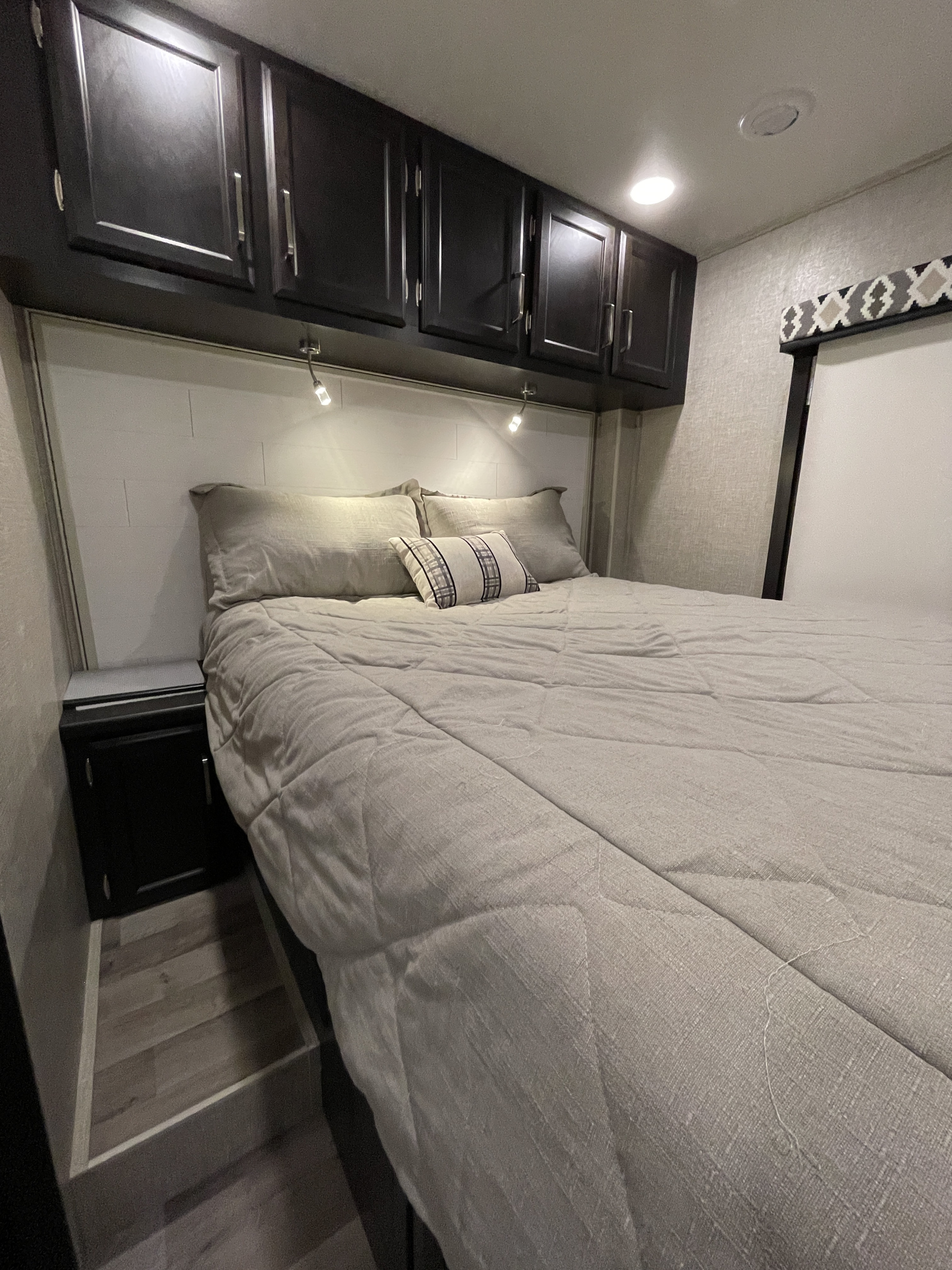 Efficient RV rental bedroom features a comfy bed, dark overhead storage, reading lights, and built-in nightstands.. Entegra Coach Vision 29S 2022