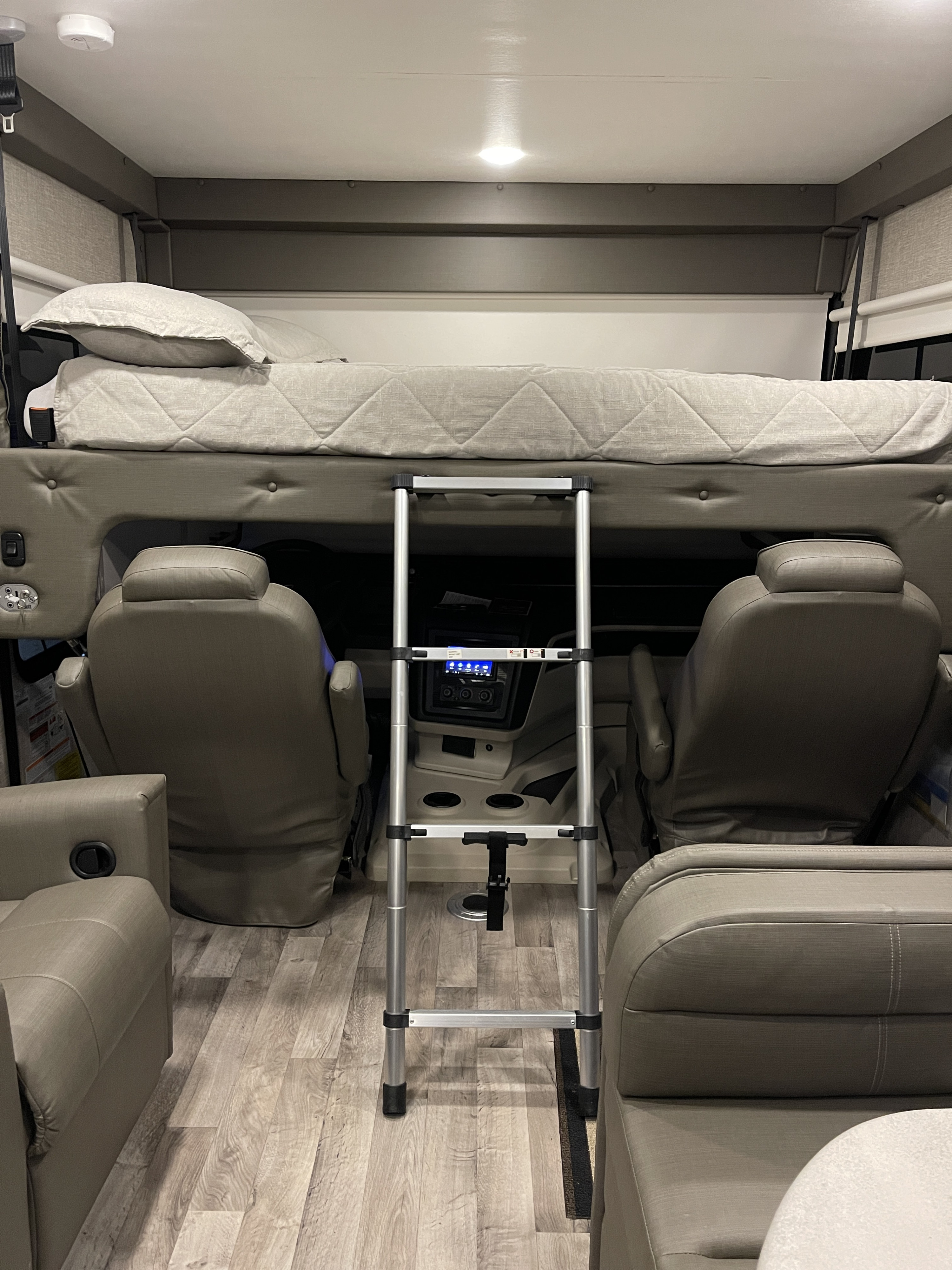 Cozy RV rental interior with an overhead bunk bed, ladder, and front cockpit area. Ideal for travel and adventure.. Entegra Coach Vision 29S 2022