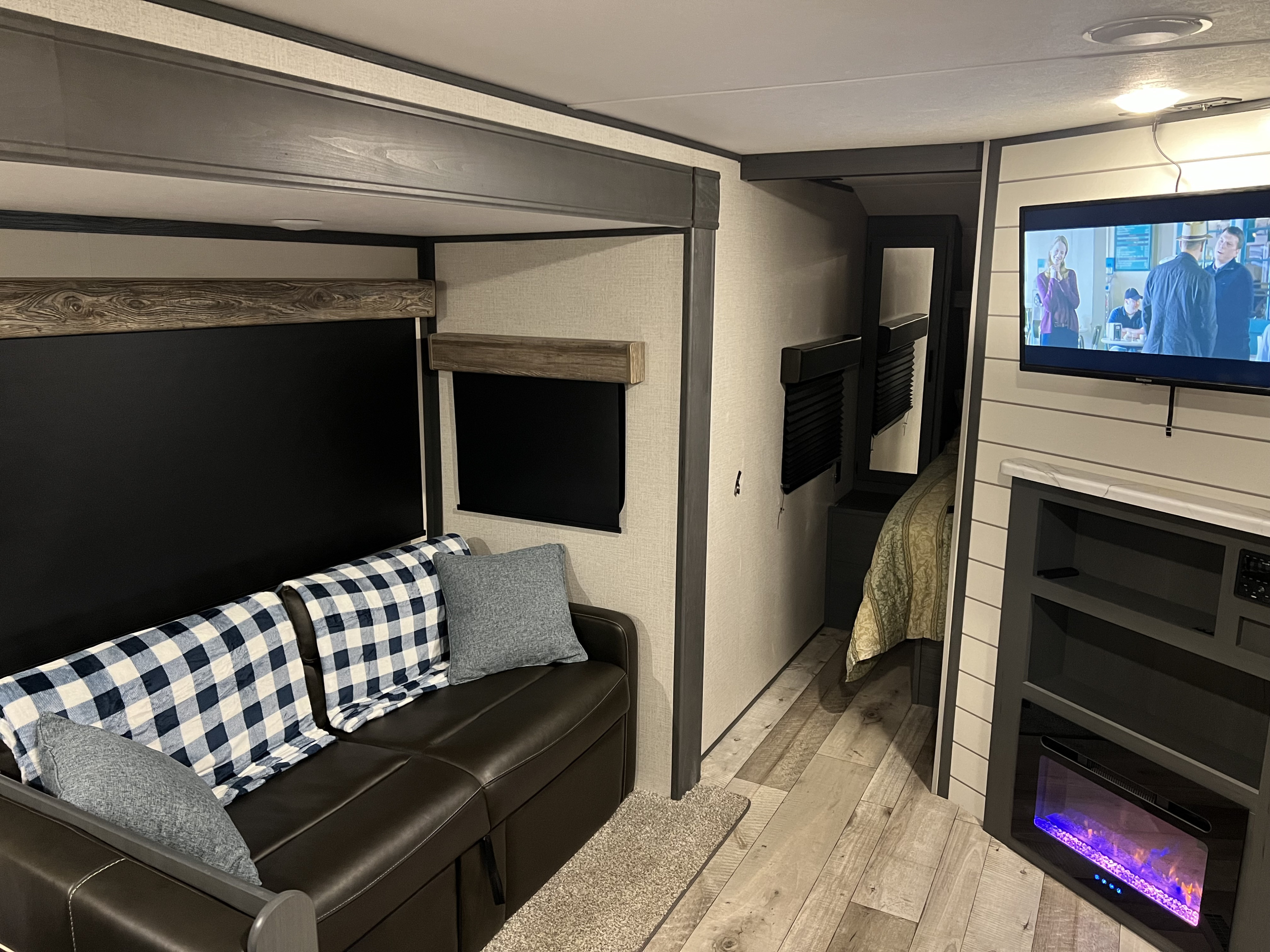 Modern RV rental interior with living area, TV, fireplace, and bedroom access.. Aspen Trail Aspen Trail Trailer 2022