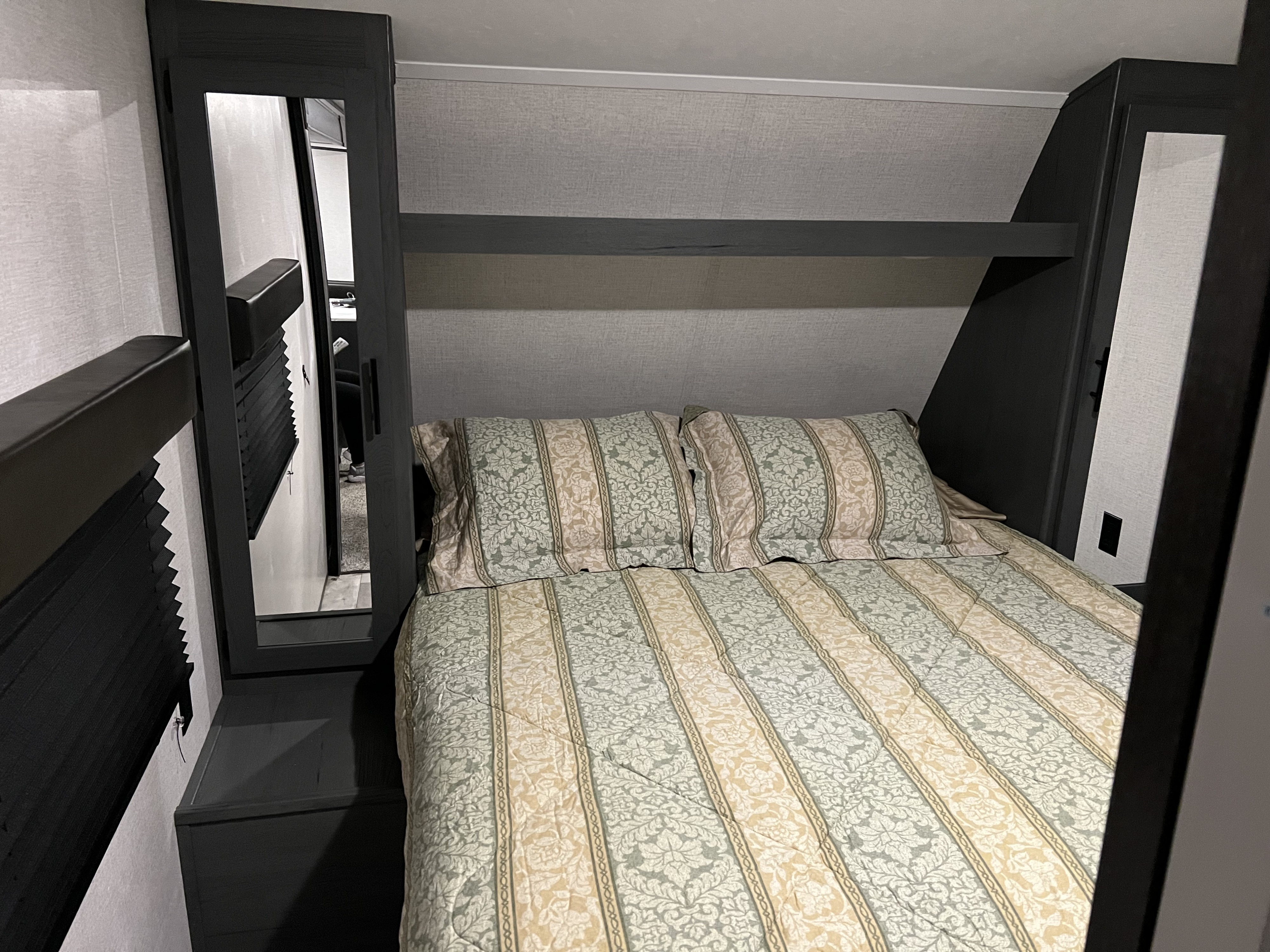 Cozy RV rental bedroom with patterned bedding, overhead storage, and mirrored wardrobe, perfect for comfortable travel.. Aspen Trail Aspen Trail Trailer 2022