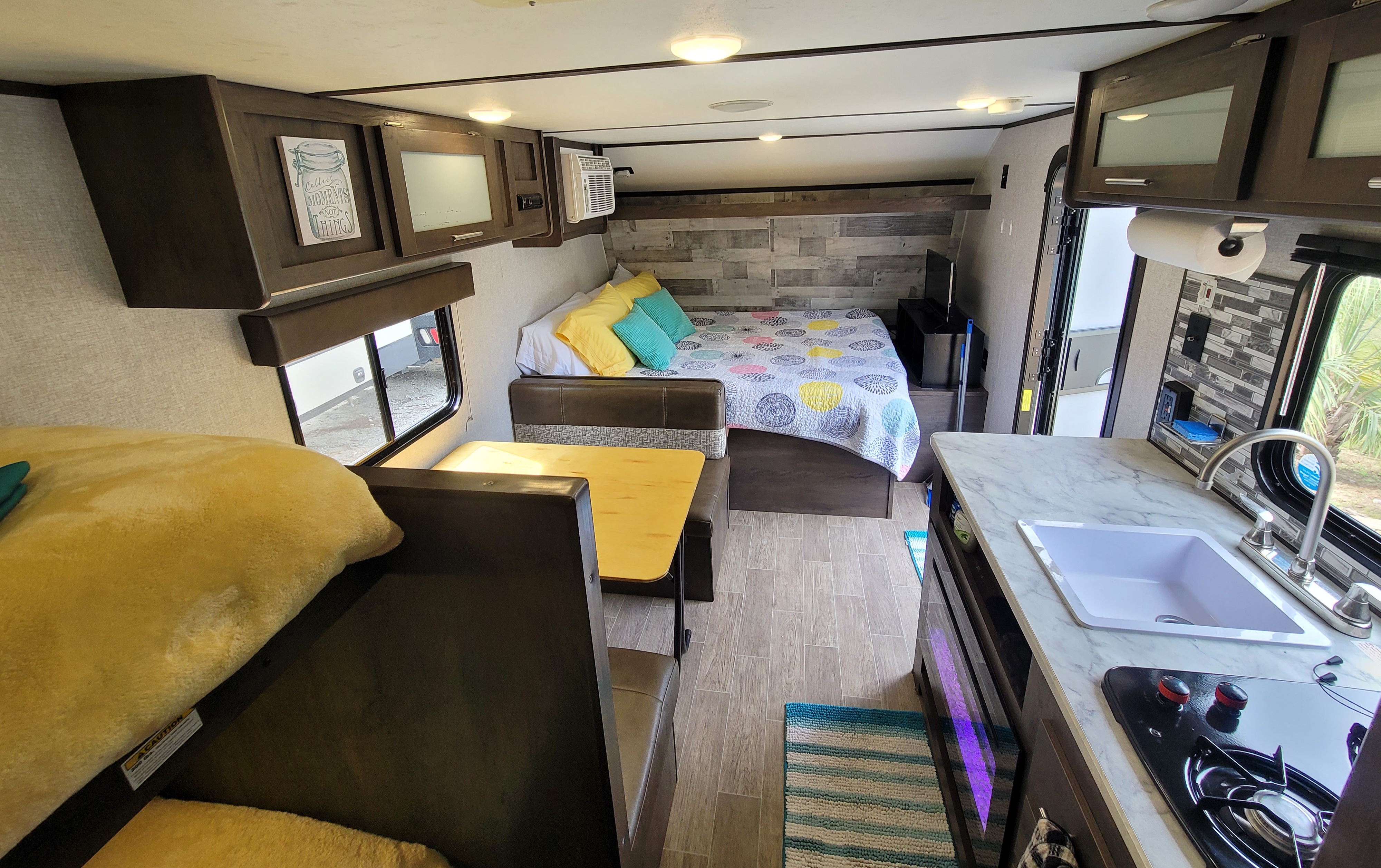 Bright rv rental interior with a comfy bed, dinette, and kitchen area. Perfect for travel and relaxation on the road.. Dutchmen Coleman 2021