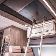 RV rental interior: A cozy camper with a ladder to an upper bunk, AC unit, and comfortable lower seating.. Ranger R540 2023