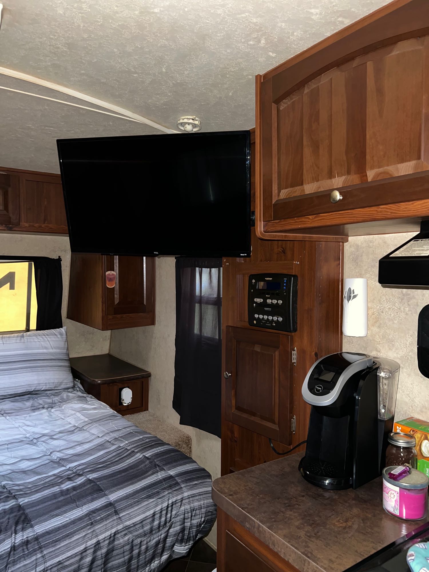 Cozy RV rental interior: Bedroom with TV, and a compact kitchen counter featuring a coffee maker and RV controls.. Forest River Flagstaff Micro Lite 2012