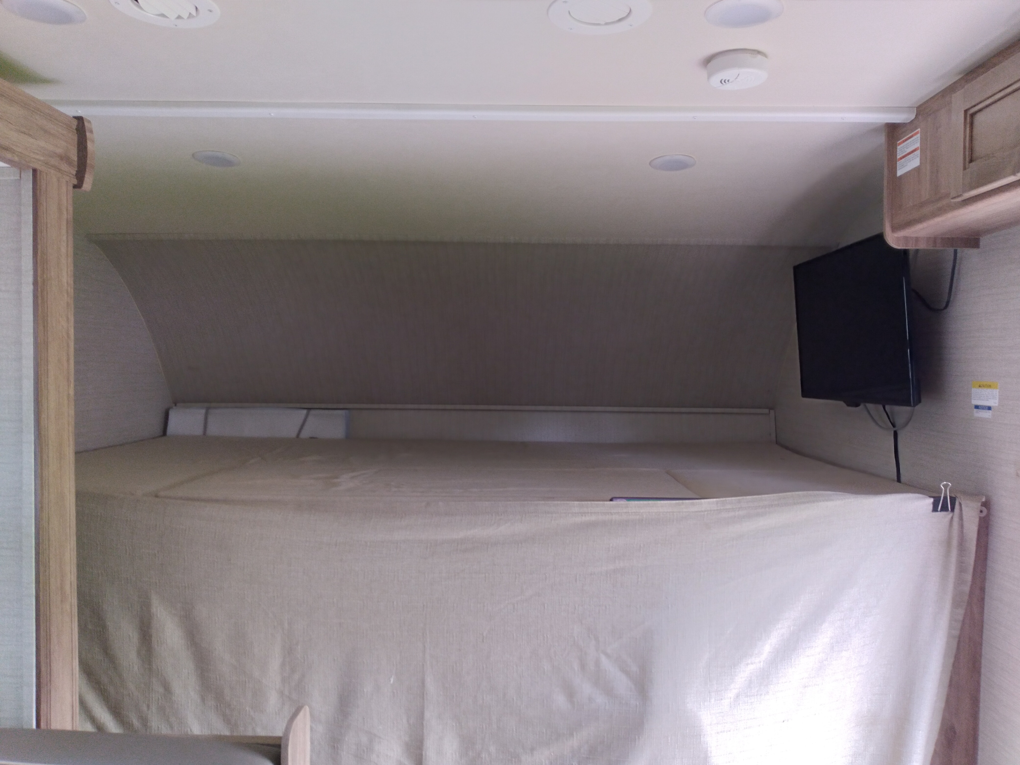 RV rental: Cozy cab-over sleeping area with a TV, light-colored bed, and overhead lights. Perfect for your adventure.. Jayco Redhawk SE 2019