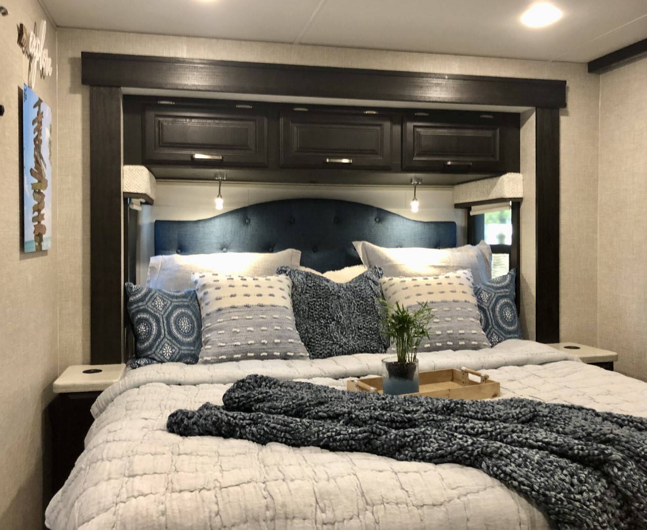 Serene RV rental bedroom featuring a large bed, blue tufted headboard, and cozy blue/white bedding.. Jayco Precept 2023