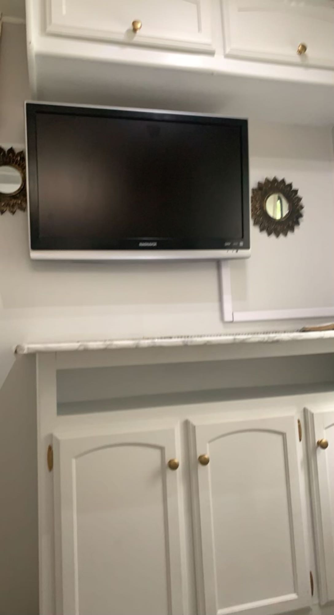 Inside a cozy rv rental: white cabinets with gold knobs, a mounted flat-screen TV, and sunburst mirrors. Compact comfort.. Dutchmen Dutchmen 2009